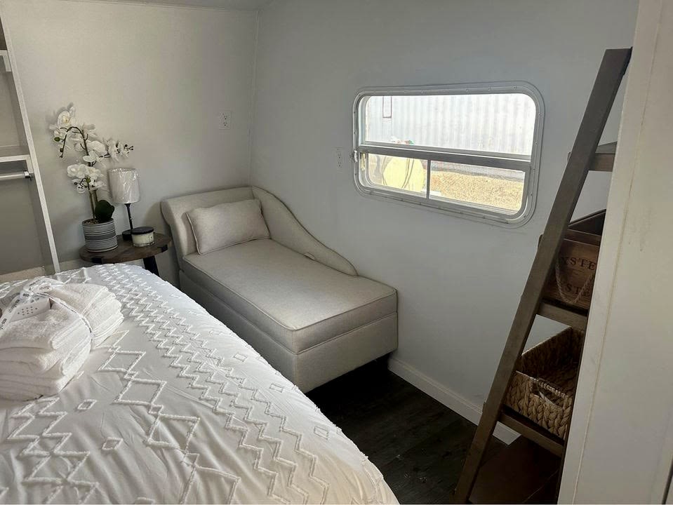 This RV rental bedroom offers a comfortable bed, chaise lounge, and practical storage, maximizing space efficiently.. Forest River Sierra Sport 2007