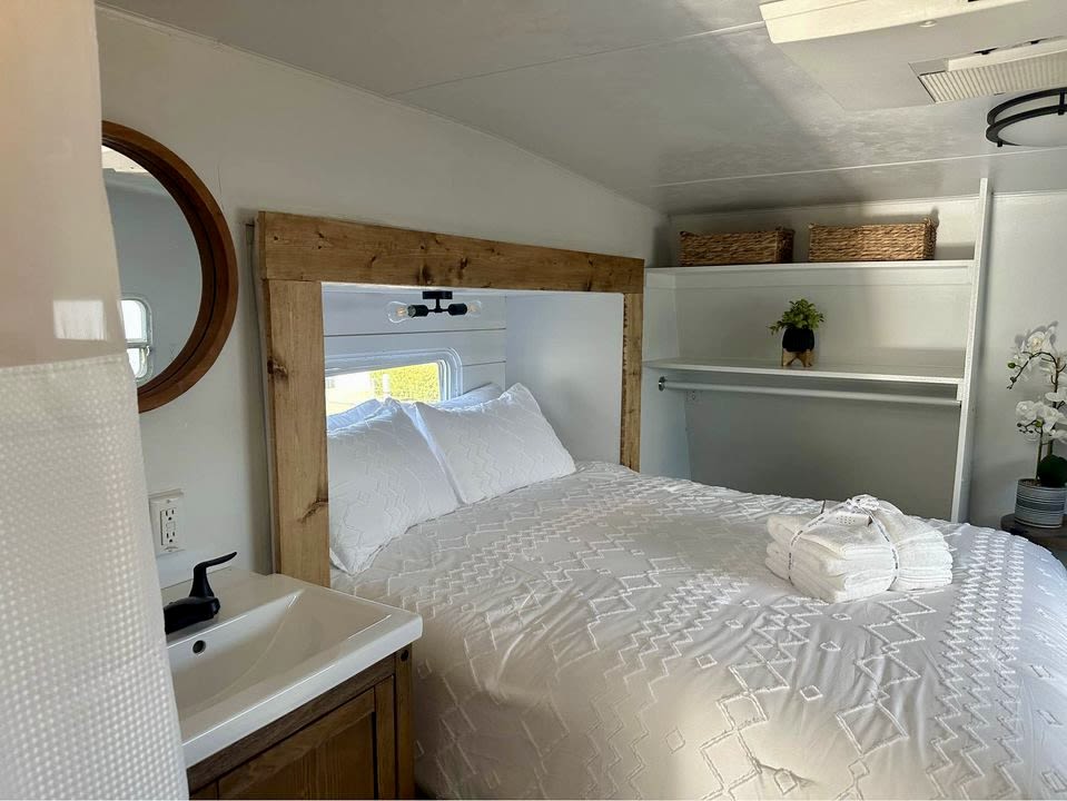 Modern RV rental interior: A bright bedroom featuring a comfy bed, sink, storage, & fresh white decor.. Forest River Sierra Sport 2007