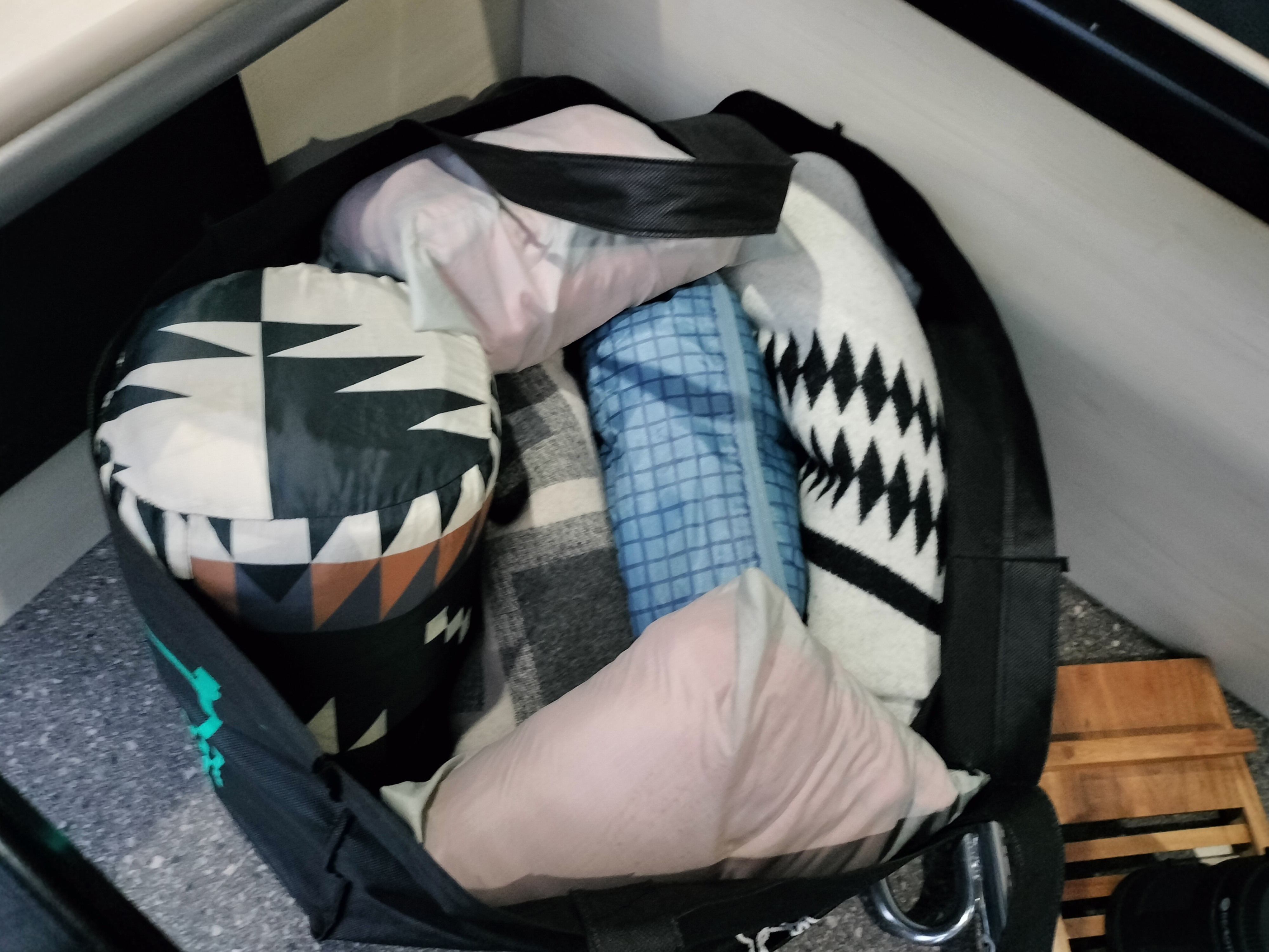 RV rental essentials: A black bag packed with bedding; geometric, zigzag, and plaid patterns, plus pink pillows.. Ram ProMaster 1500 Tofino Camper Van 2023