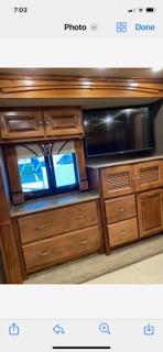 RV rental bedroom interior featuring a TV, wooden cabinets, drawers, and a window. Provides ample storage.. Tiffin Motorhomes Phaeton 2016