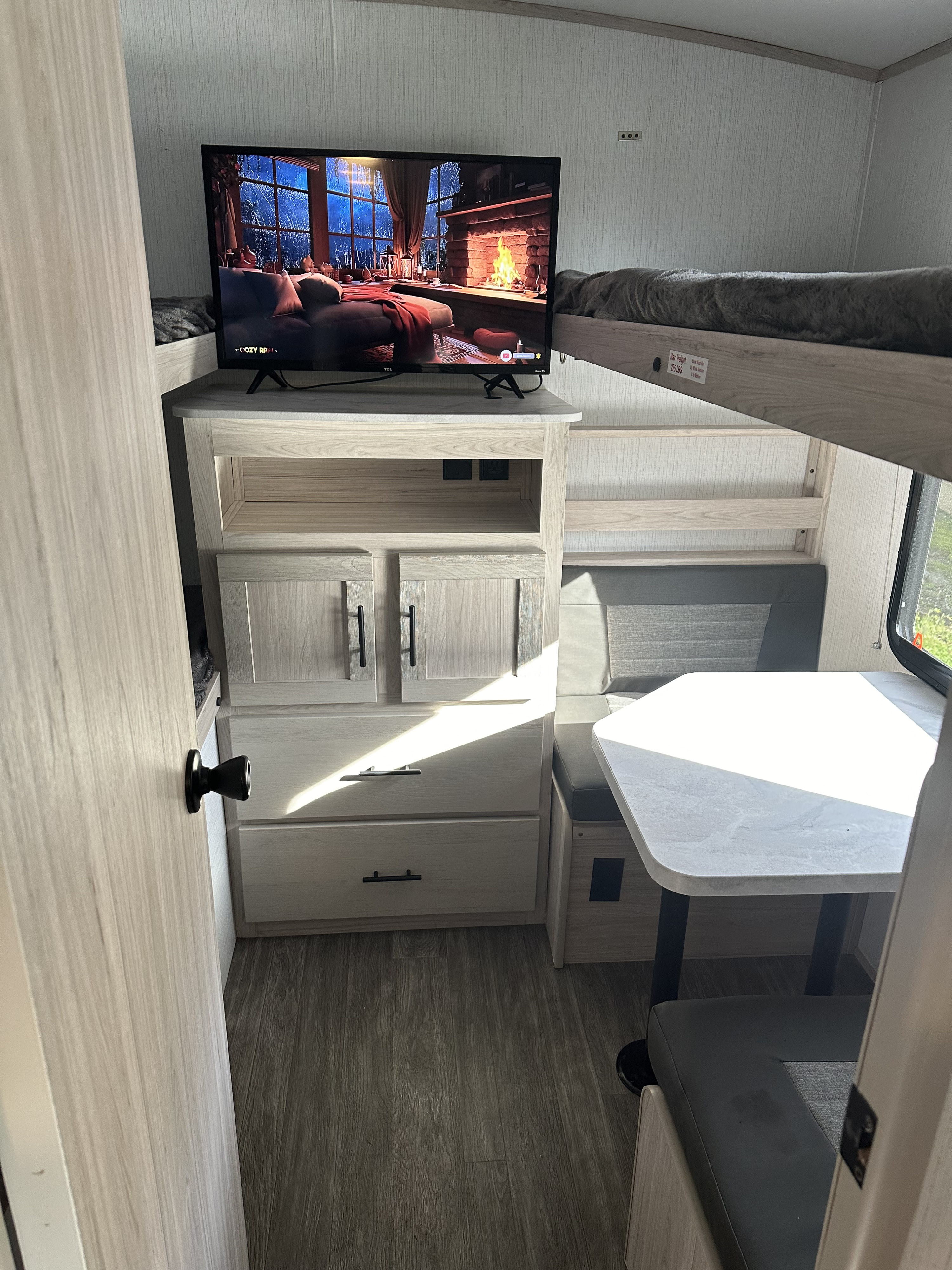 An RV rental interior featuring a TV, cozy bunk beds, and a dinette area.. Cruiser RV Shadow Cruiser 2023