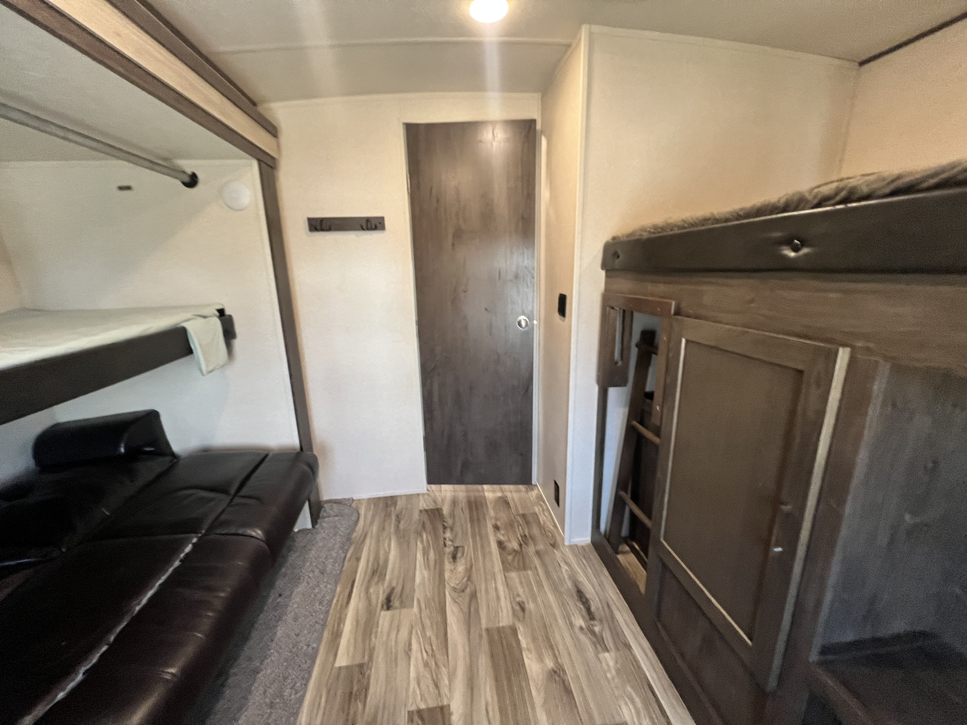 RV rental interior with bunk beds, a black couch, and wood-patterned flooring, providing a cozy living space.. Forest River Heritage Glen 2018