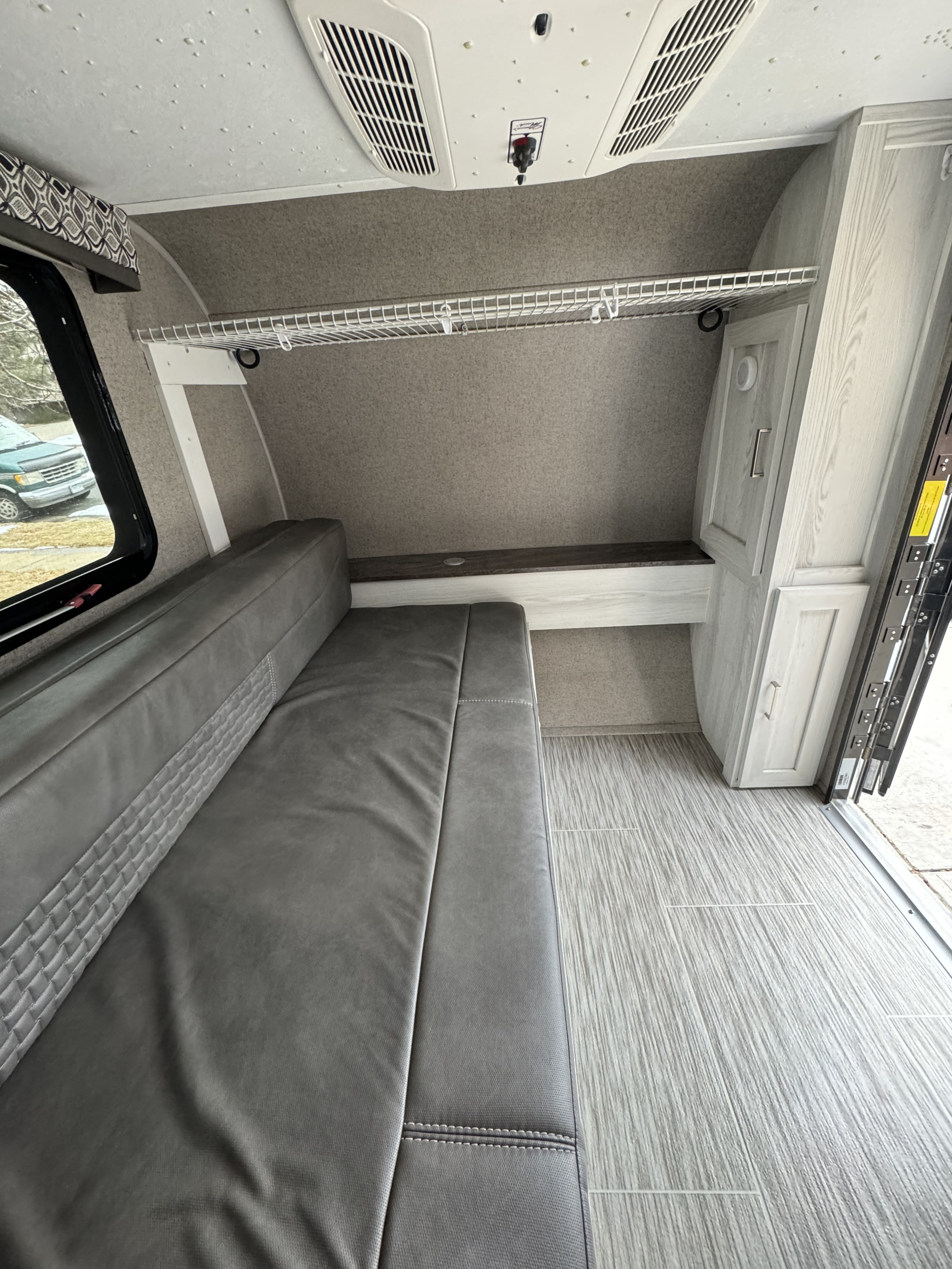 RV rental interior shows grey dinette/bed, ceiling AC, wire shelf, and light wood-look flooring.. Forest River Rockwood Geo Pro 2019