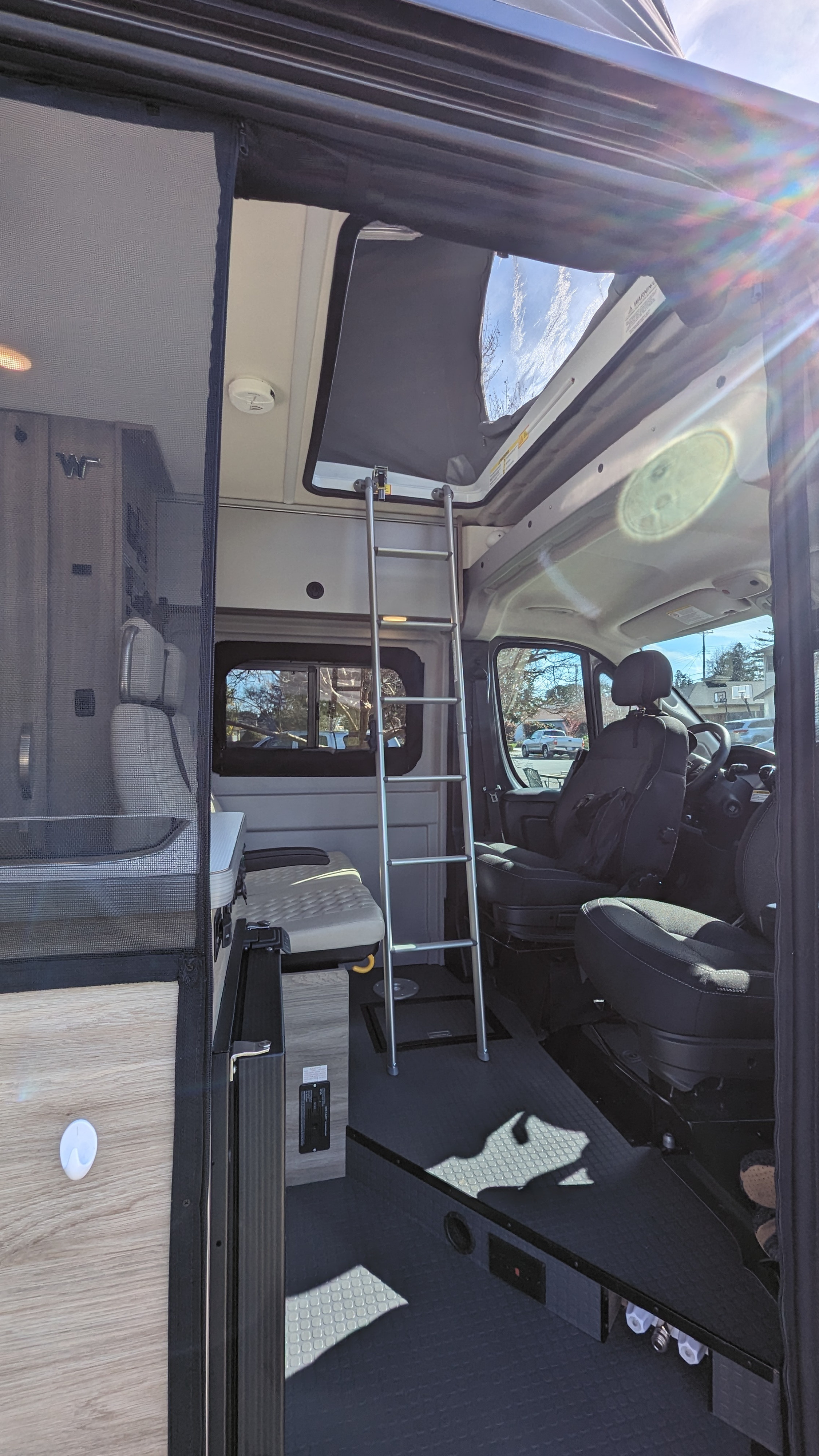 RV rental: Bright camper van interior with ladder to a pop-top bed, front seats, and a spacious rear living area.. Winnebago Solis 2023