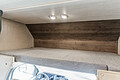Cozy cab-over sleeping area in an RV rental, featuring a comfortable bunk, integrated lighting, and stylish wood-look wall.. Nexus RV Triumph 2022