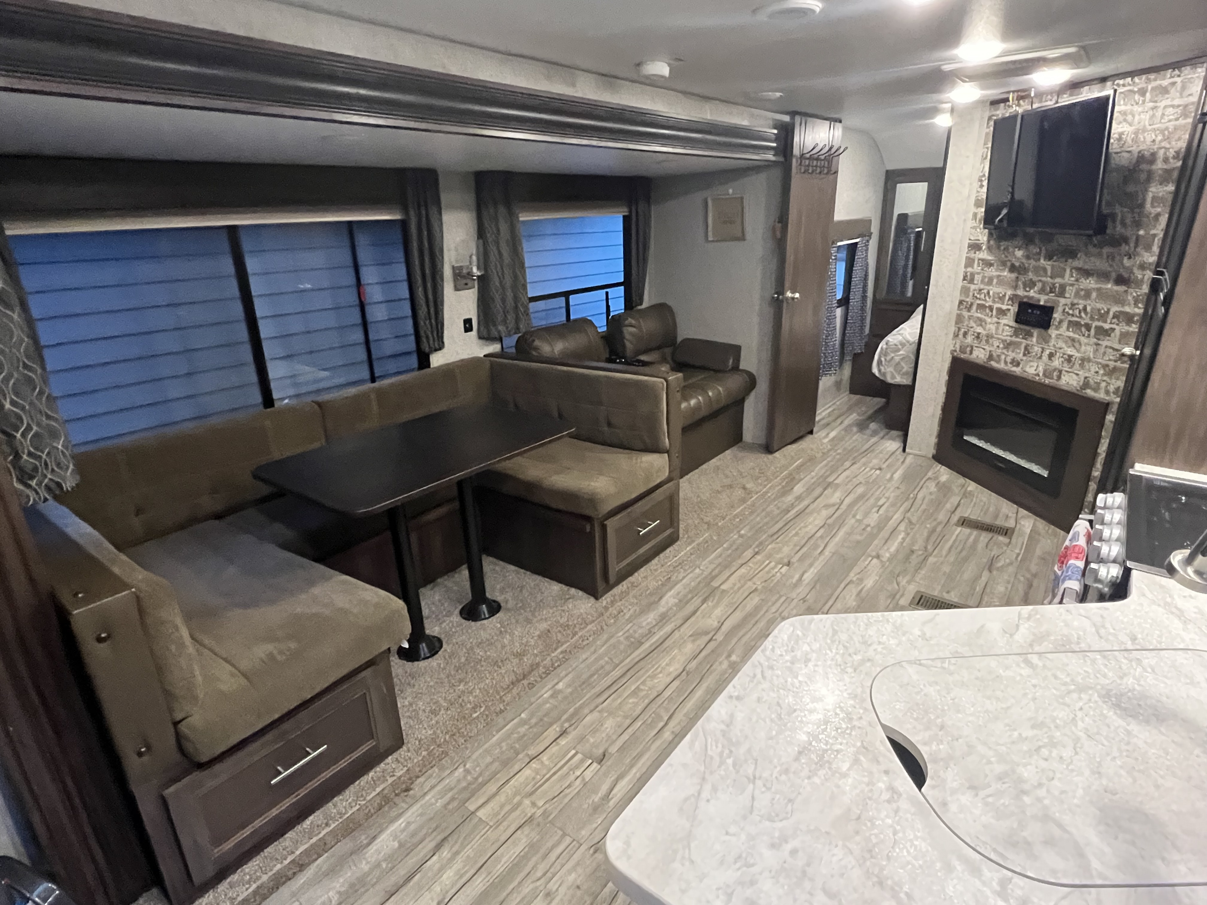 Inviting rv rental interior with a U-shaped dinette, lounge seating, kitchen counter, TV, and fireplace.. Forest River Cherokee 2019
