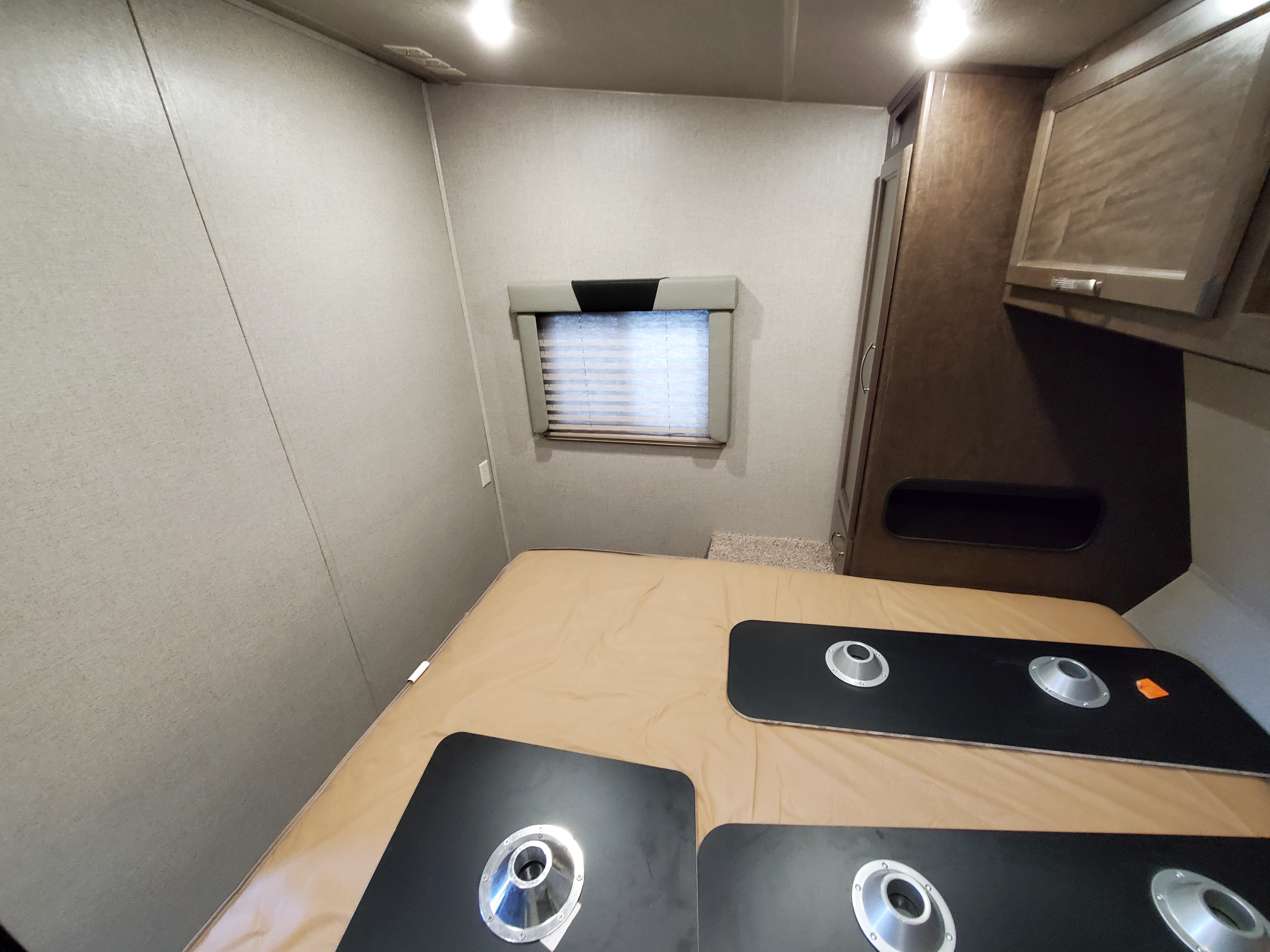An **rv rental**'s cozy sleeping area, featuring a bed, small window, and built-in storage. Table mounts are visible on the mattress.. Genesis Supreme Rv 25fs 2020