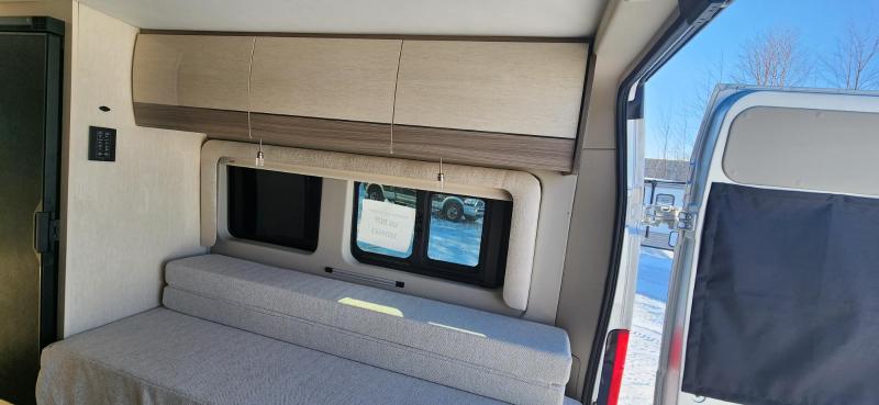 Cozy RV rental interior showing a comfortable bed/seating area, overhead cabinets, and windows for your next adventure.. Entegra Coach Ethos 2023