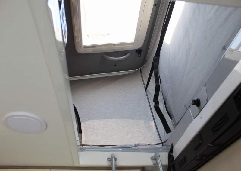 Spacious elevated pop-up sleeping area in an RV rental, featuring light fabric walls and a large roof window.. Entegra Coach Ethos 2023