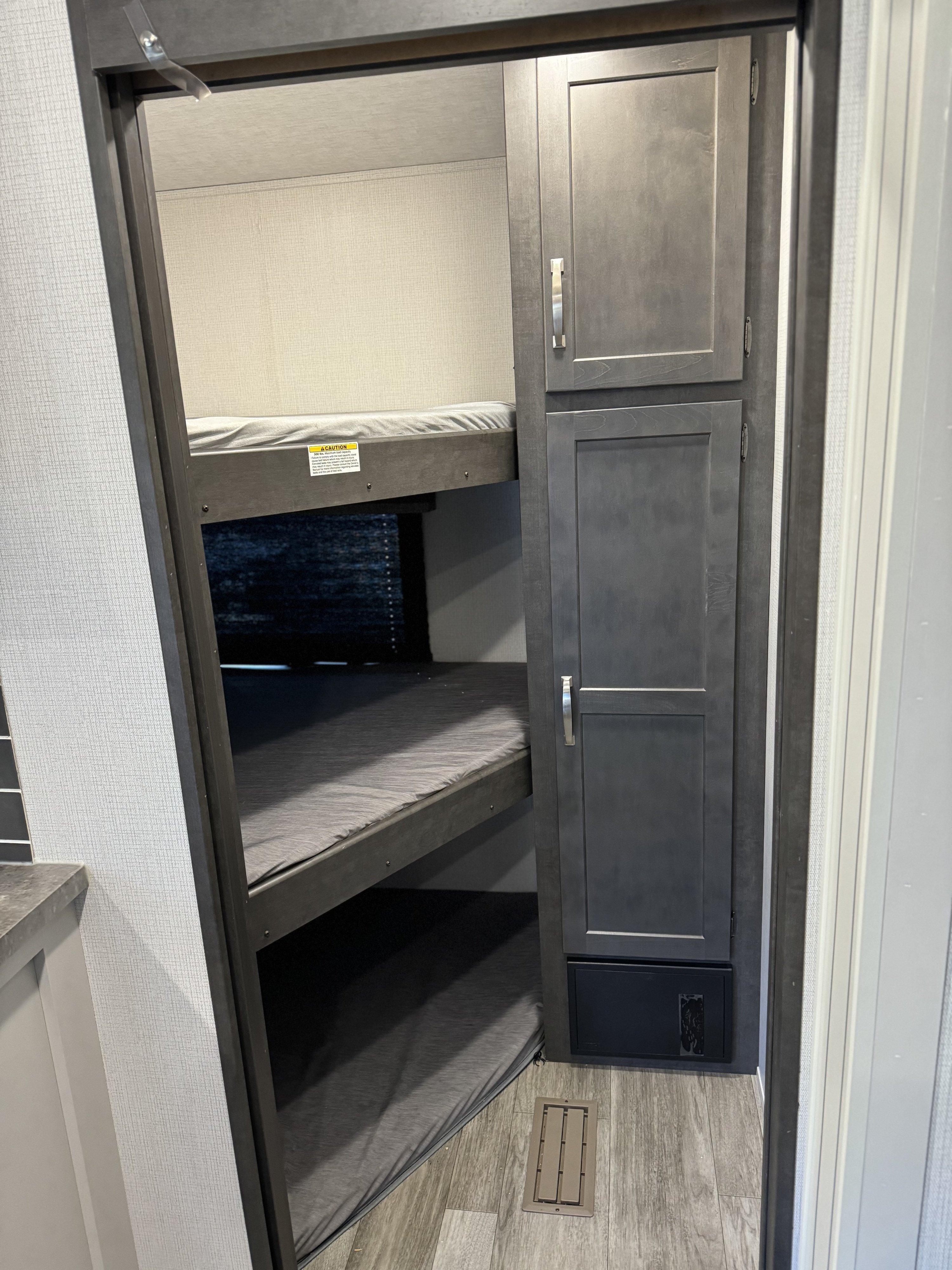 RV rental interior: dark grey stacked bunk beds with soft mattresses, and an adjacent storage cabinet.. Keystone Cougar Sport 2024
