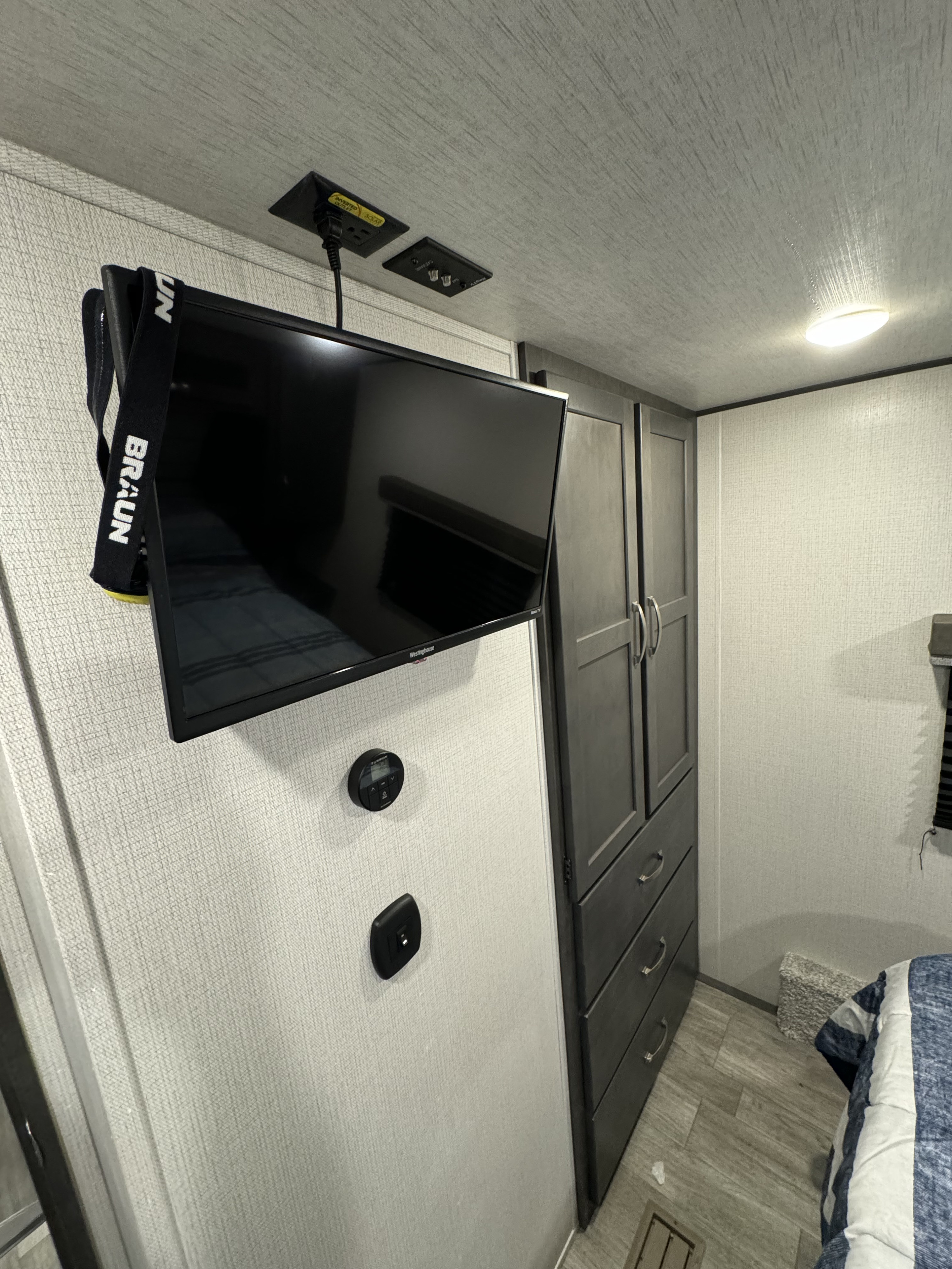 RV rental's modern bedroom: wall-mounted TV, storage, and RV-specific power outlets, including solar.. Keystone Cougar Sport 2024