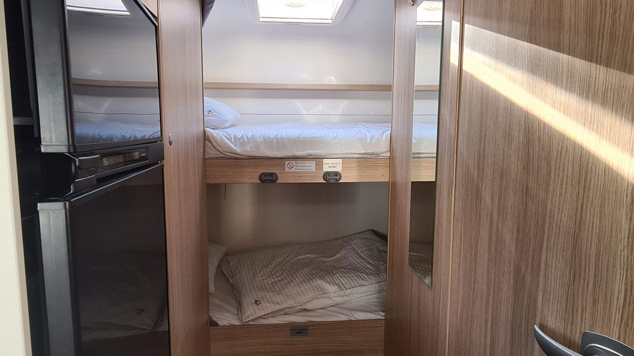 Compact and cozy RV rental interior featuring bunk beds and a built-in fridge, perfect for family adventures.. Sunlight A68 2024