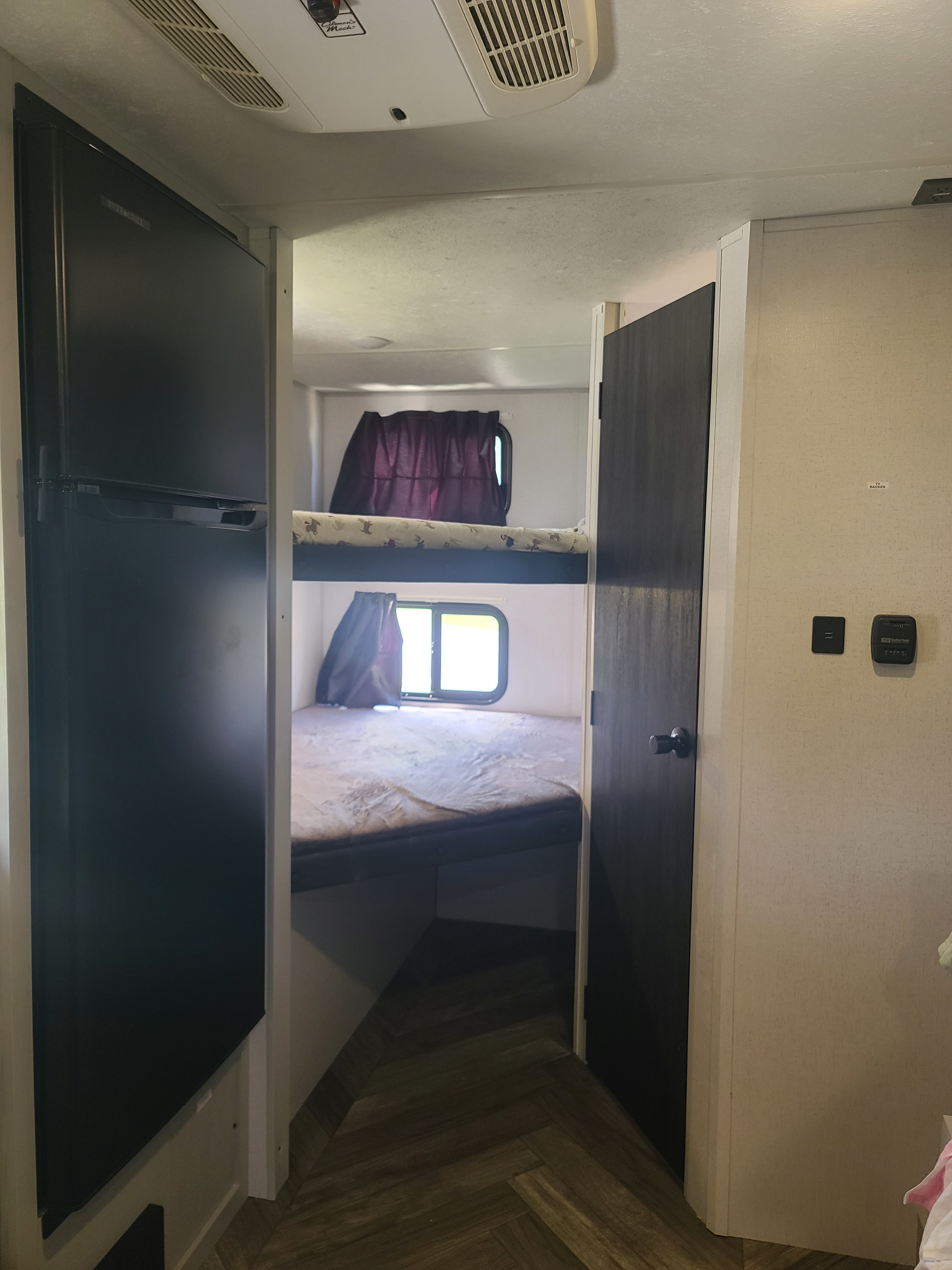 RV rental interior: View of the bunk bed area, with a dark refrigerator on the left and wall controls on the right.. Forest River Salem FSX 2022
