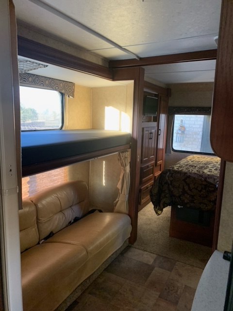 RV rental interior: bunk beds, leather sofa, and bedroom with a patterned comforter, creating a cozy living space.. Forest River Sunseeker 2013
