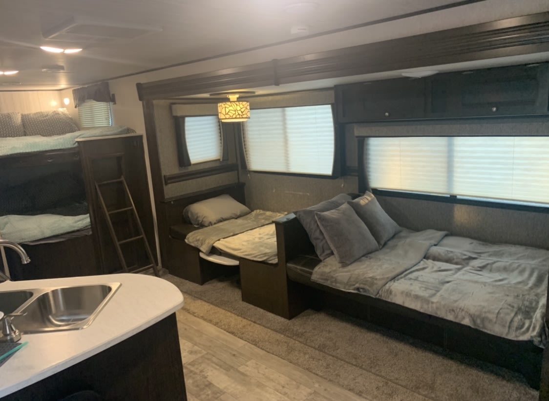 Inside an RV rental: bunk beds, convertible sleeping areas, kitchen sink, and windows with blinds offer a cozy space.. Heartland Pioneer 2020