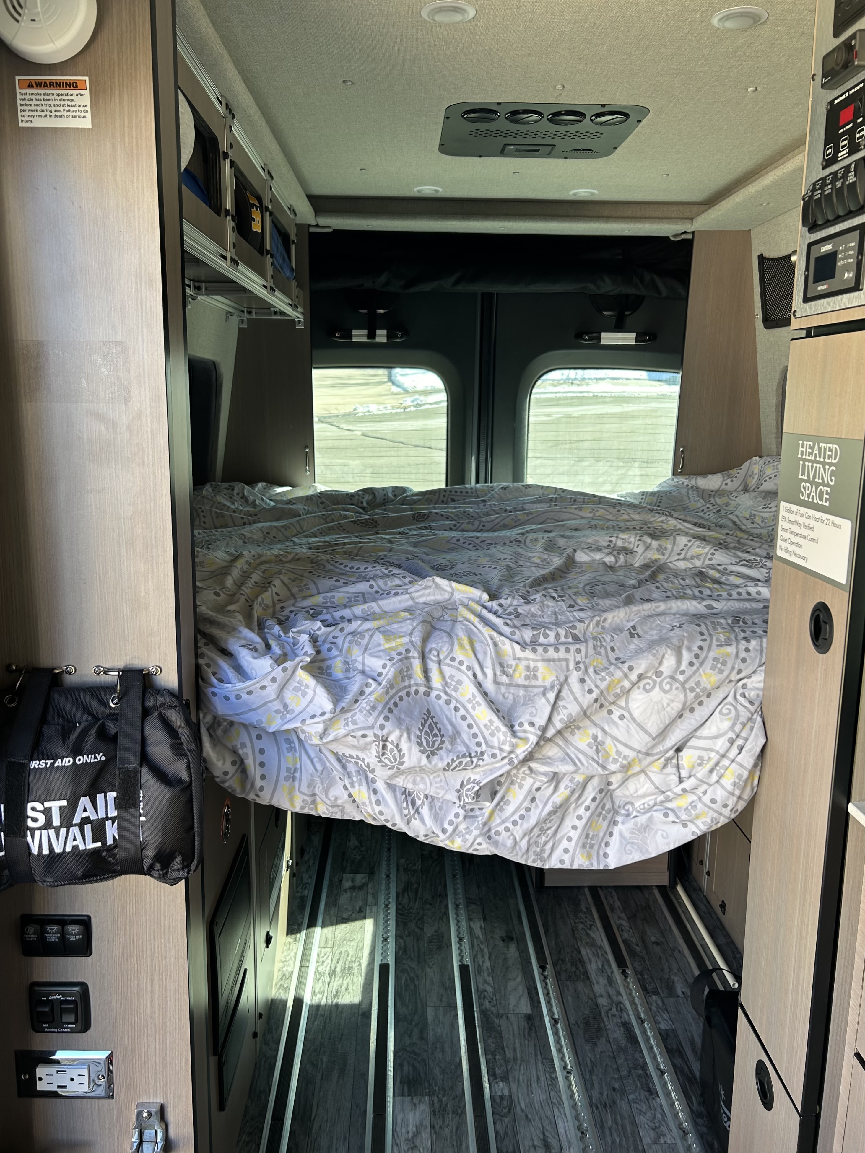Inside an RV rental: a comfy bed awaits, with climate control, utility panels, and floor tracks for gear.. Antero Adventure Motors Antero Adventure Motors Class B 2022