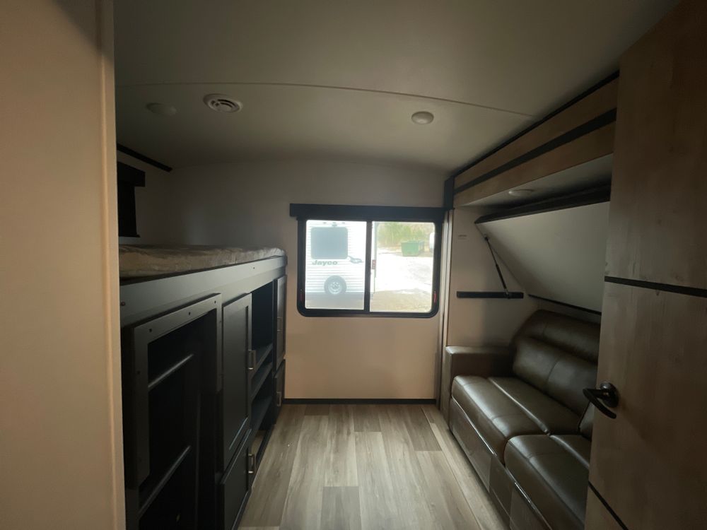 Cozy rv rental interior: bunk beds, storage, and sofa-bed create a compact, functional living space for travel.. Keystone RV Outback 2023