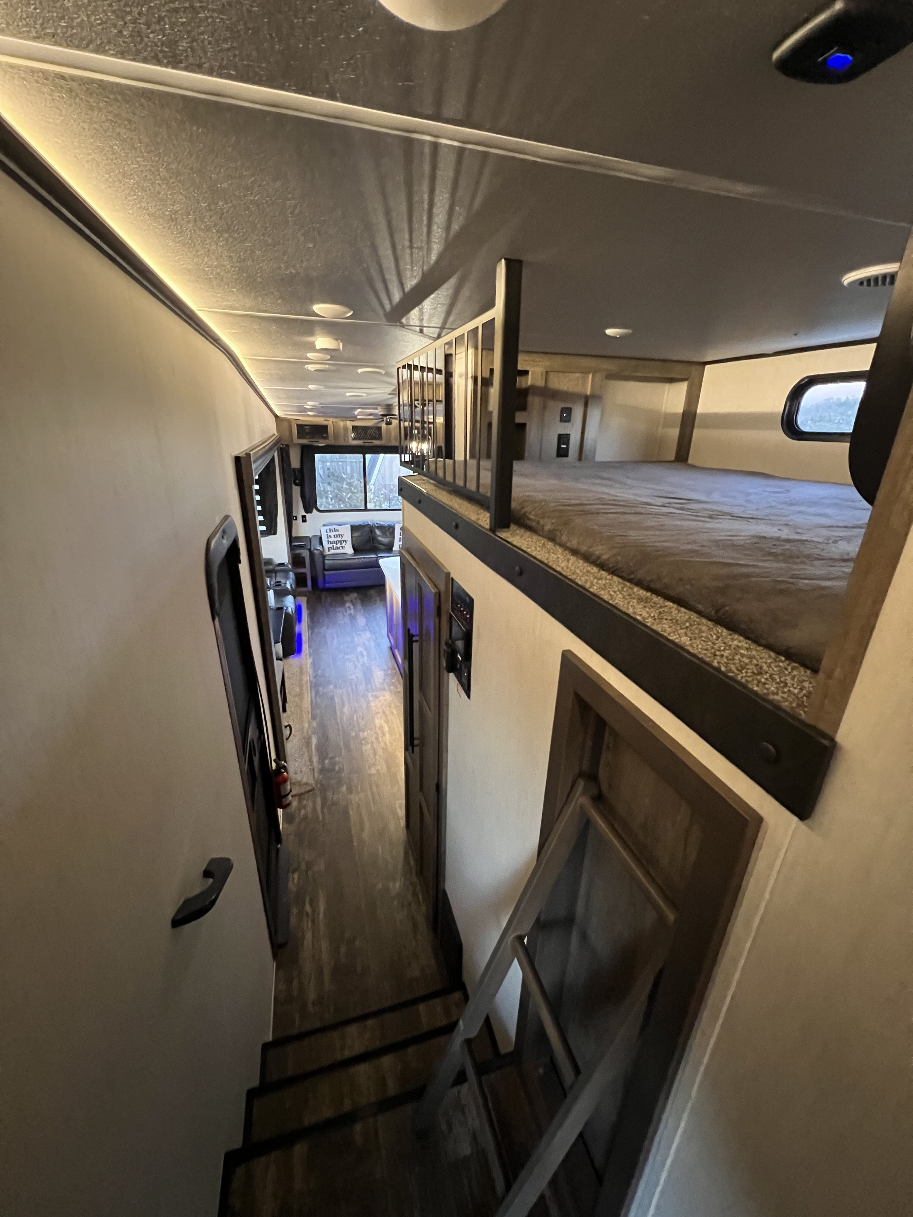 Explore this RV rental's inviting interior: long hallway, cozy living area, and an accessible loft bed with stairs.. Forest River Sabre 2021