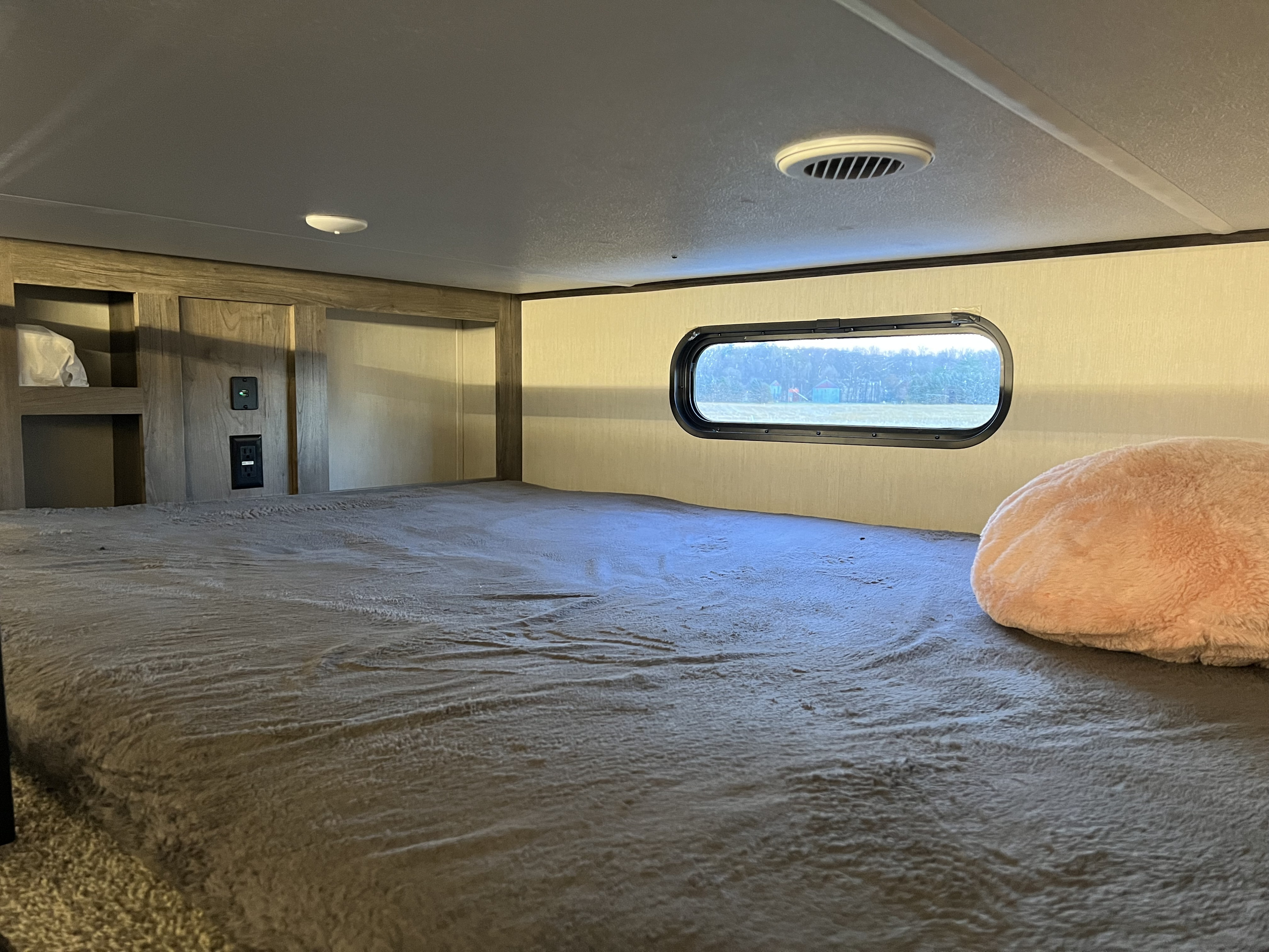 Inside an RV rental: a cozy bunk bed with a window view, lights, and charging ports.. Forest River Sabre 2021