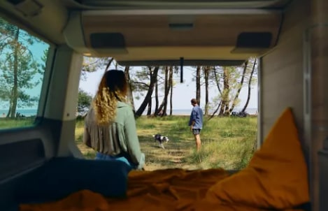 From an RV rental, two people and a dog enjoy a scenic natural setting with trees and water. Perfect for outdoor adventure.. Volkswagen California T6.1 DSG 2024