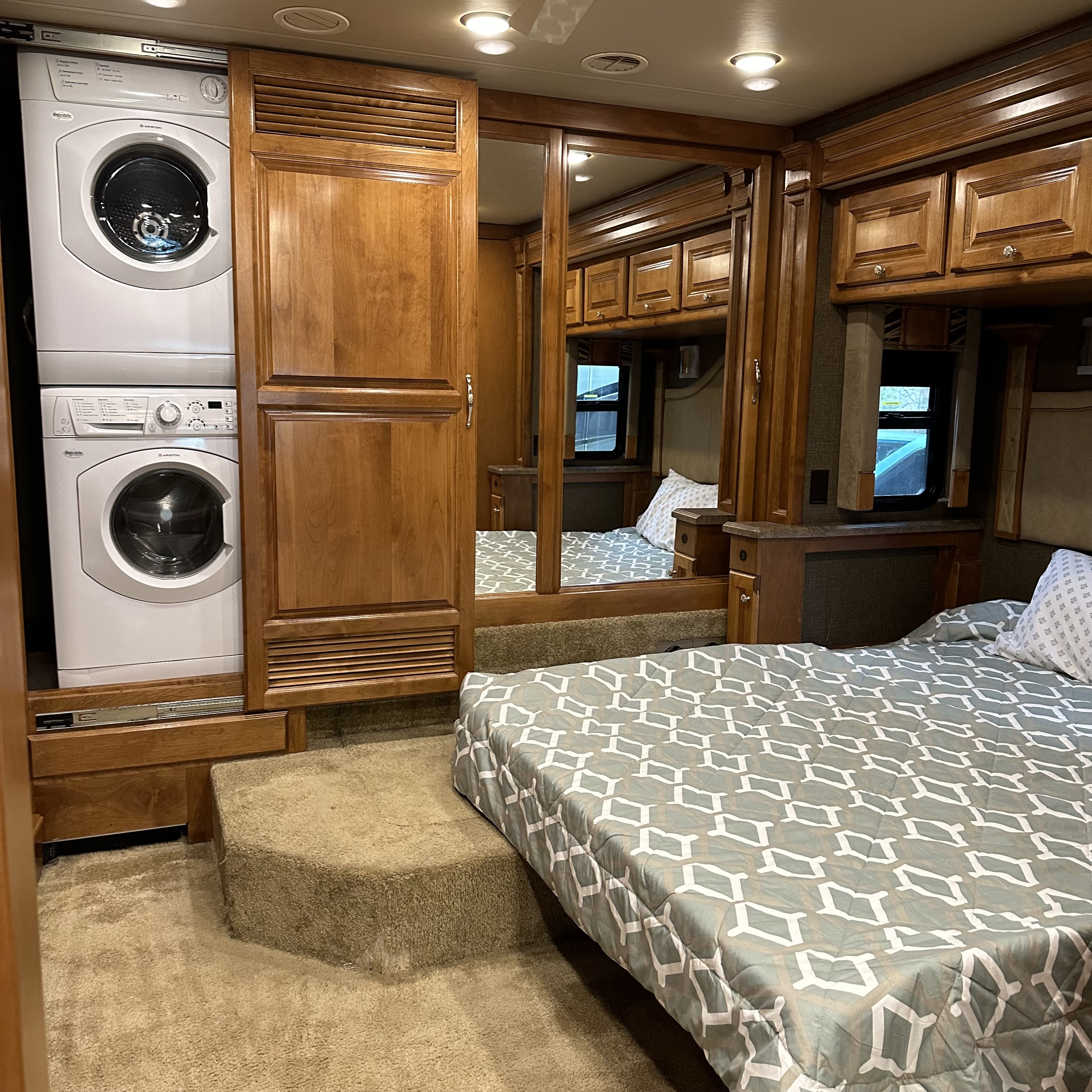 RV rental bedroom: stacked washer/dryer, mirrored closet, and a comfy bed on a raised platform. Ideal for extended trips.. Allegro Allegro Red 2016