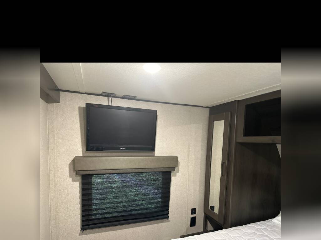 RV rental interior: Bedroom with TV, window blinds, and built-in wood cabinets.. Grand Design Other 2022