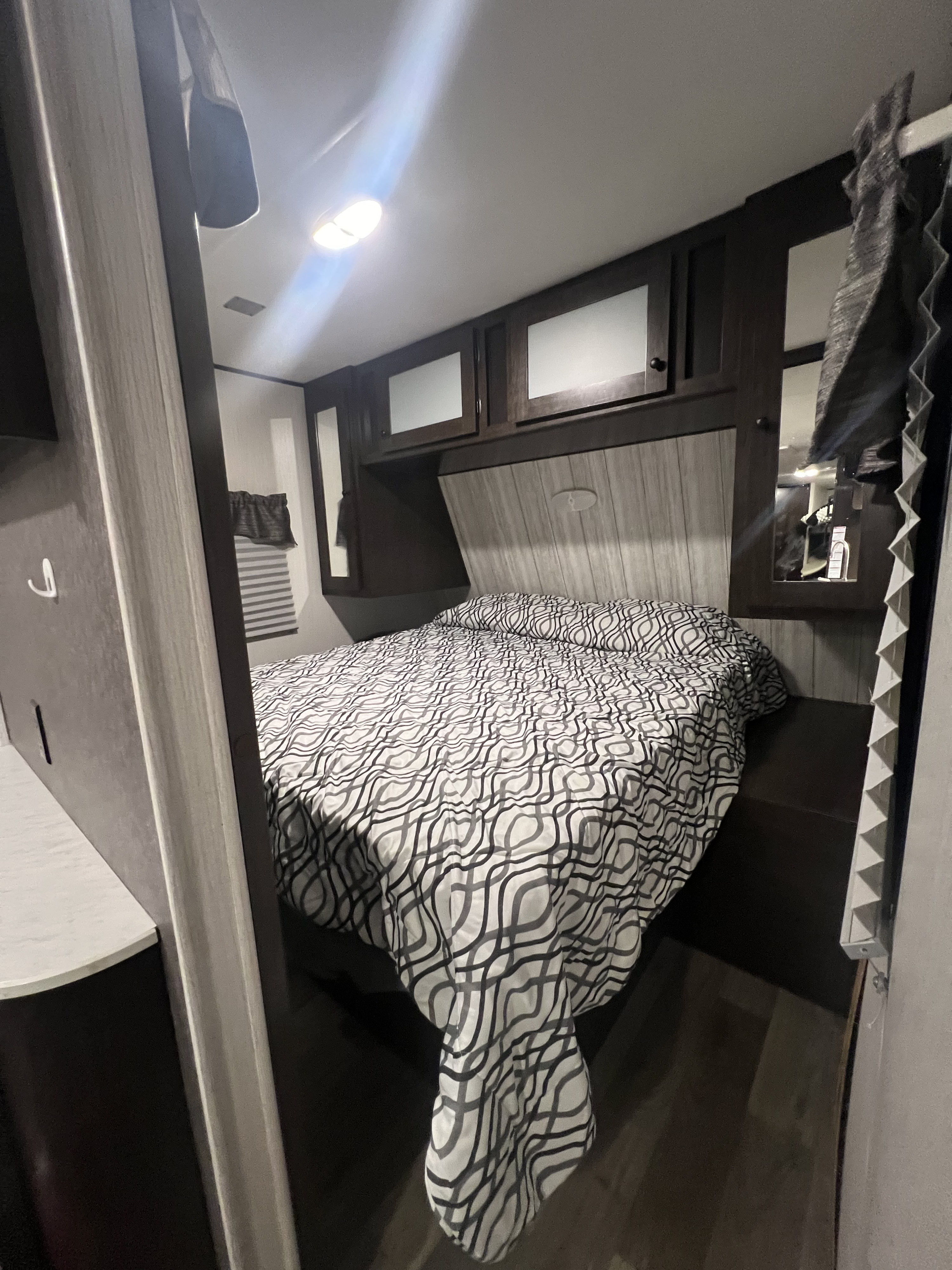 Cozy RV rental bedroom with patterned comforter, overhead storage, and modern decor, offering a comfortable stay.. Heartland RVs Pioneer 2020