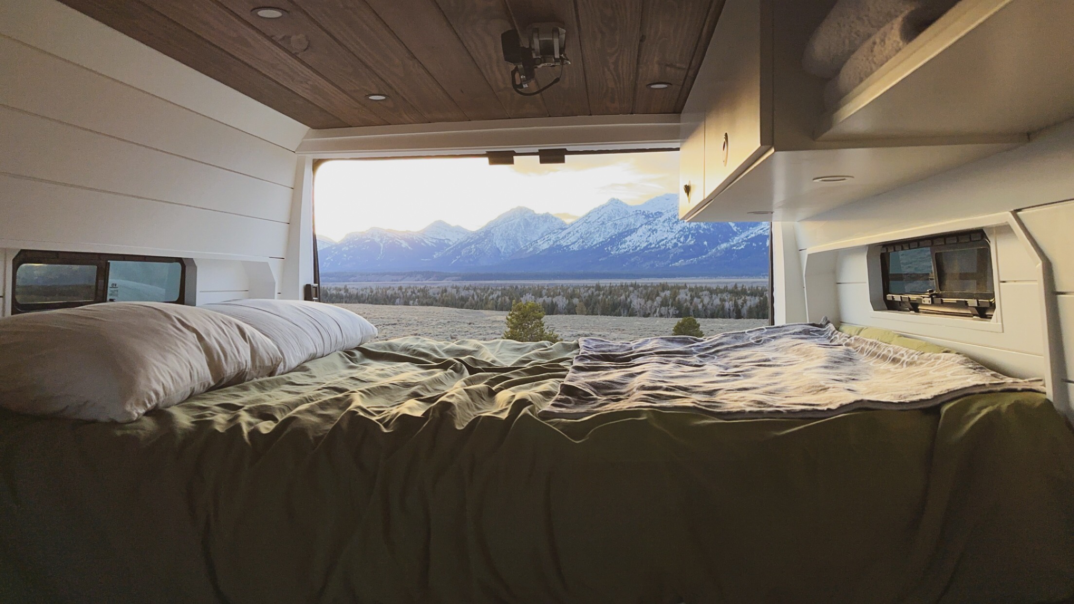 Relax in an RV rental bed with stunning views of snow-capped mountains at sunrise/sunset. Perfect for memorable adventures.. RAM ProMaster 2500 2022