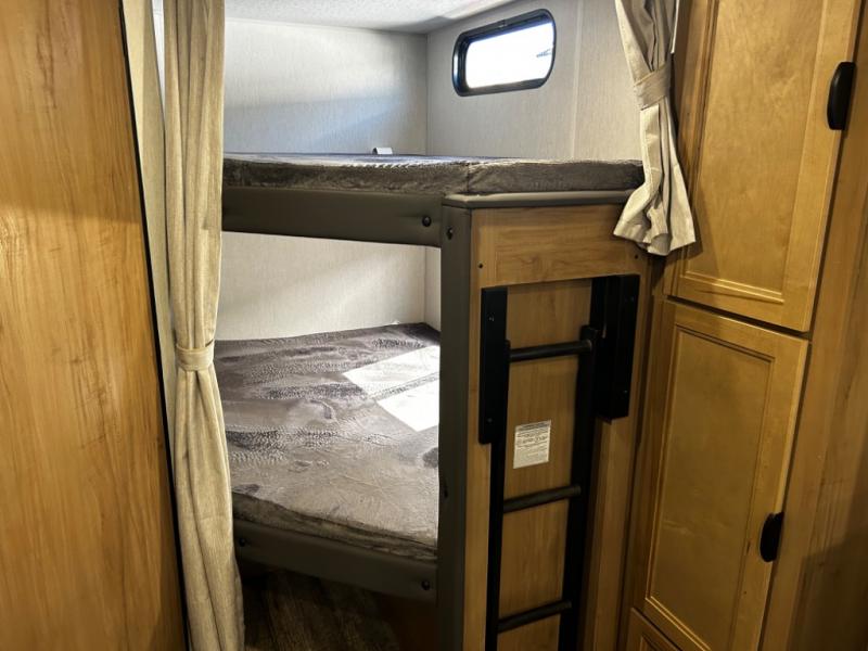 Inside an RV rental: a compact bunk bed setup with ladder, window, and wood cabinetry for cozy sleeping.. Forest River Cherokee Grey Wolf 23DBH 2024