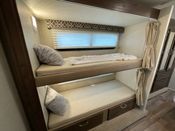 RV rental bunk beds: a cozy sleeping area with two stacked bunks, complete with pillows, individual lighting, and window blinds.. Jayco Redhawk 2019