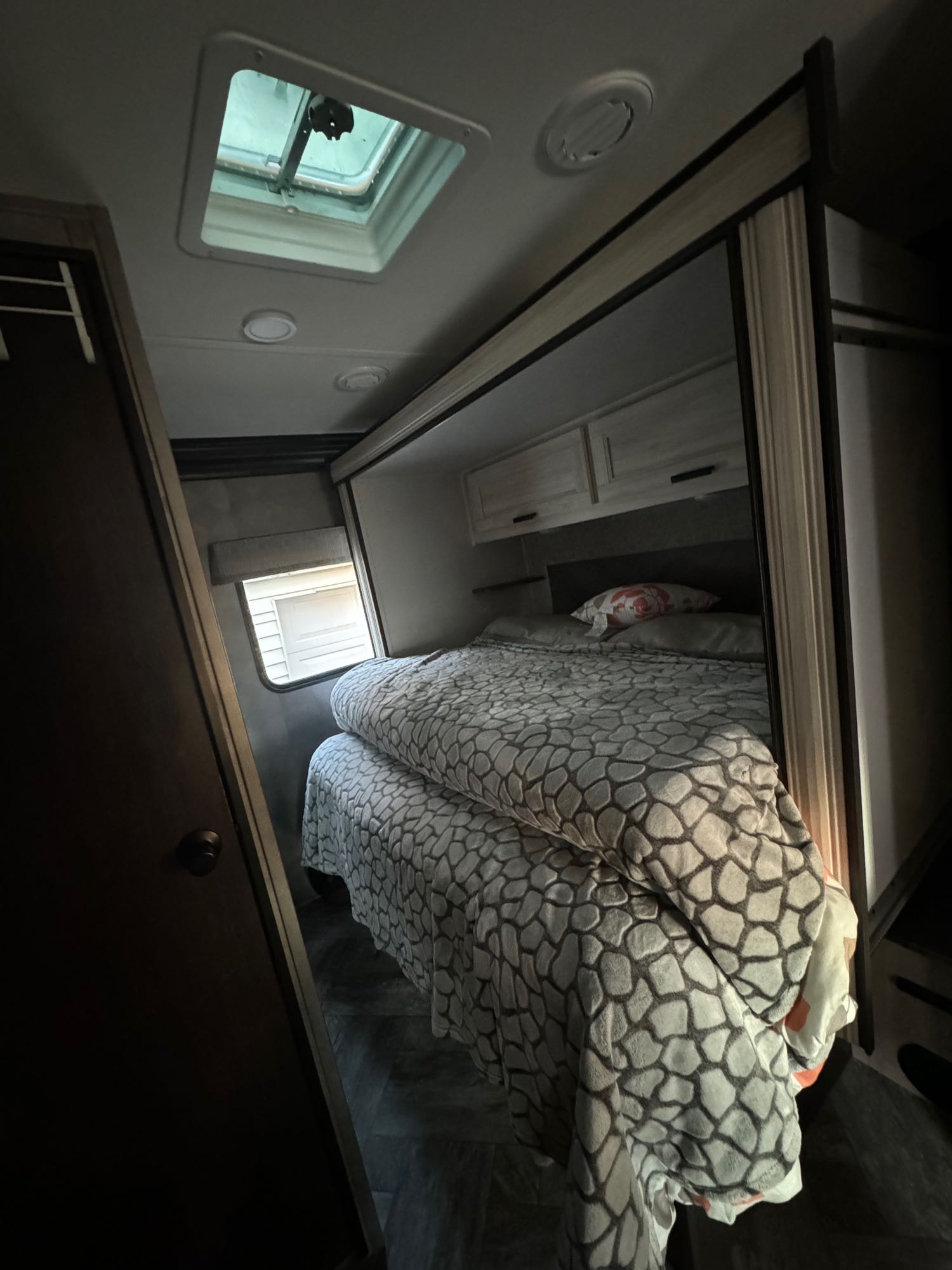 RV rental: Compact bedroom showing patterned blanket on bed, overhead storage, window, and roof vent.. Forest River Sunseeker LE 2022