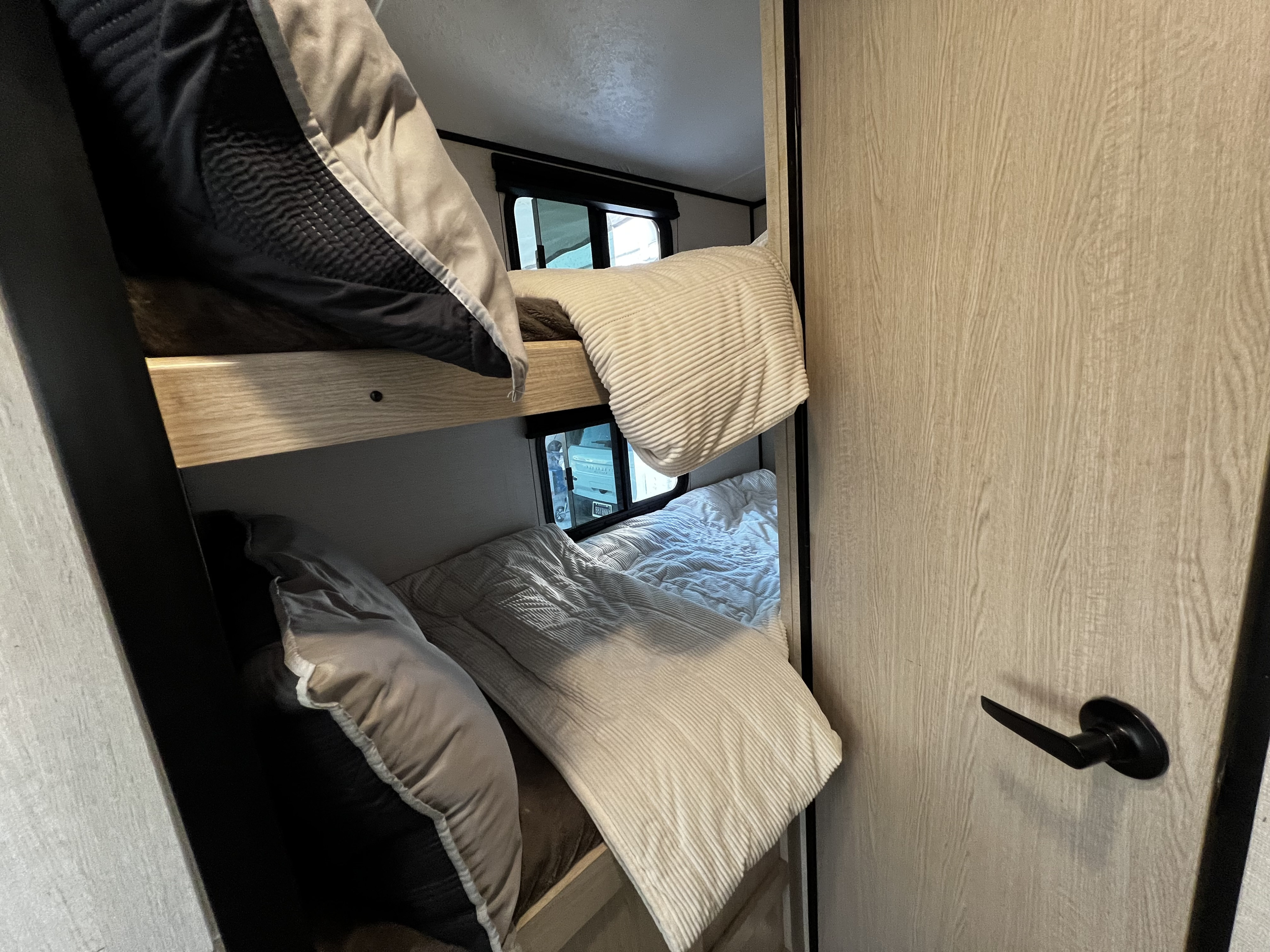 This RV rental features two cozy bunk beds with light and dark bedding, designed for compact comfort.. Coachmen Apex Nano 2022