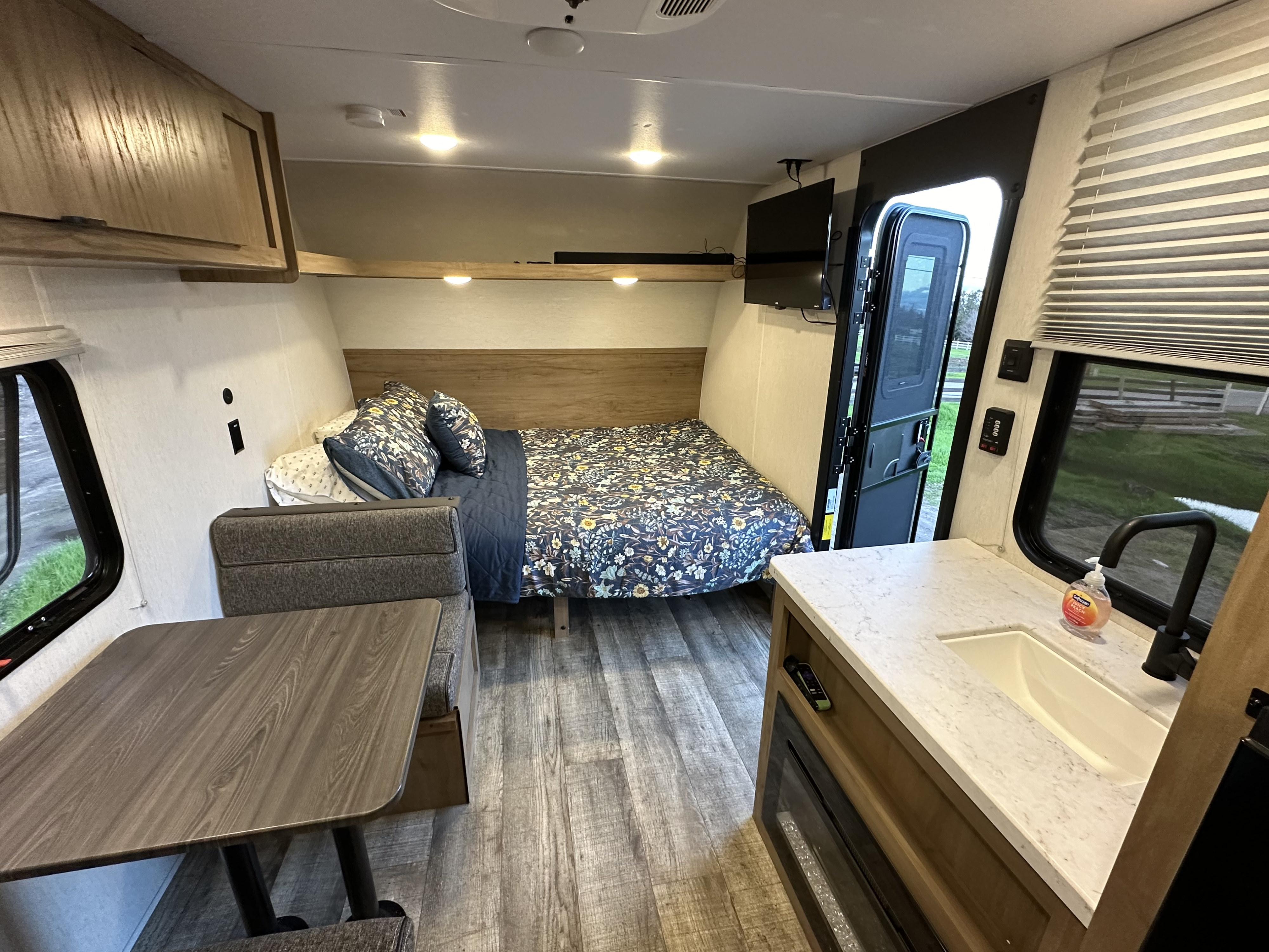 Cozy rv rental interior with a bed, dinette, kitchenette, sink, and TV for comfortable travel.. Forest River Cherokee Wolf Den 16 EV 2024