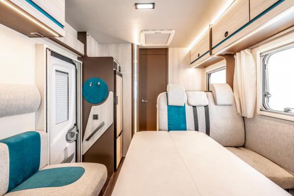 Bright, modern RV rental interior featuring a convertible bed/dining area, comfy seating, and built-in storage.. Rimor Kilig 695 2024