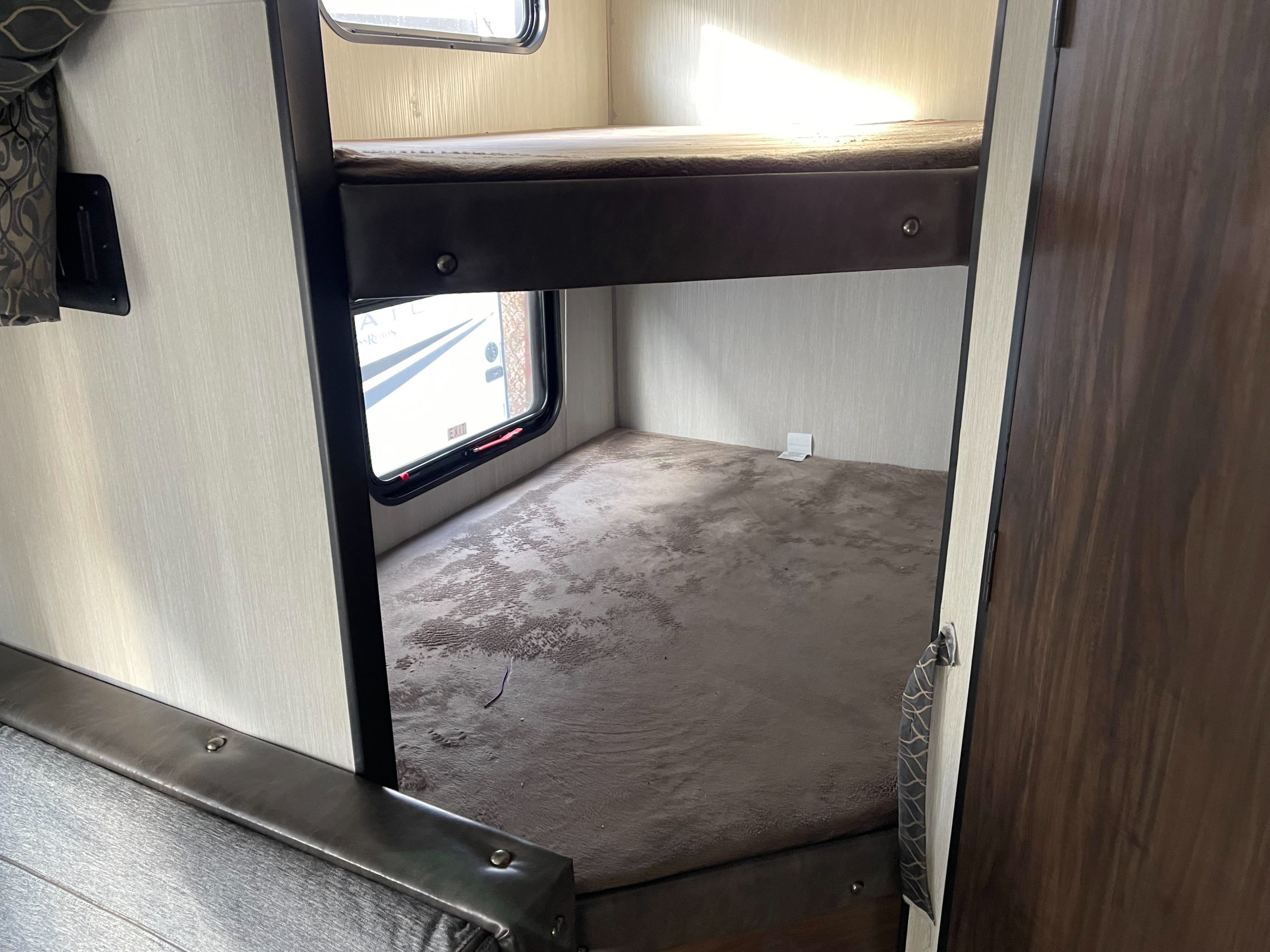 RV rental: Interior view of compact bunk beds, featuring an upper and lower sleeping area, a window, and textured floor.. Forest River Cherokee Grey Wolf 2019