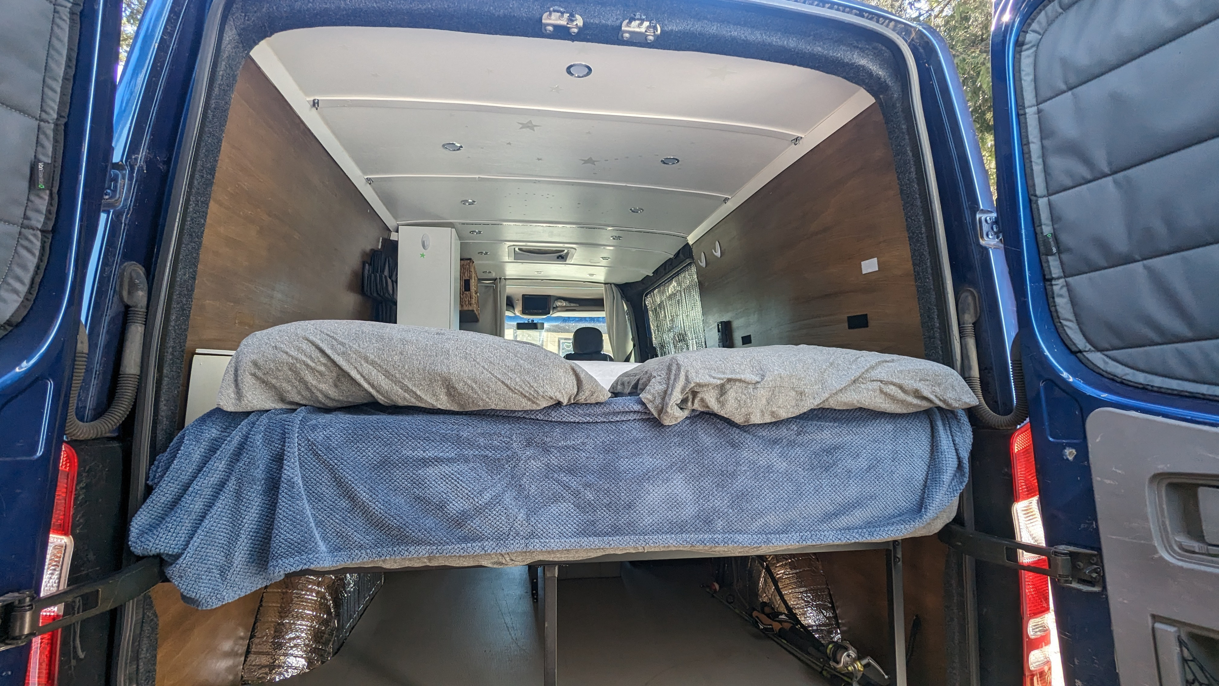 Looking into a blue RV rental from the rear, showing a comfy bed and convenient under-bed storage.. Dodge Sprinter 2007