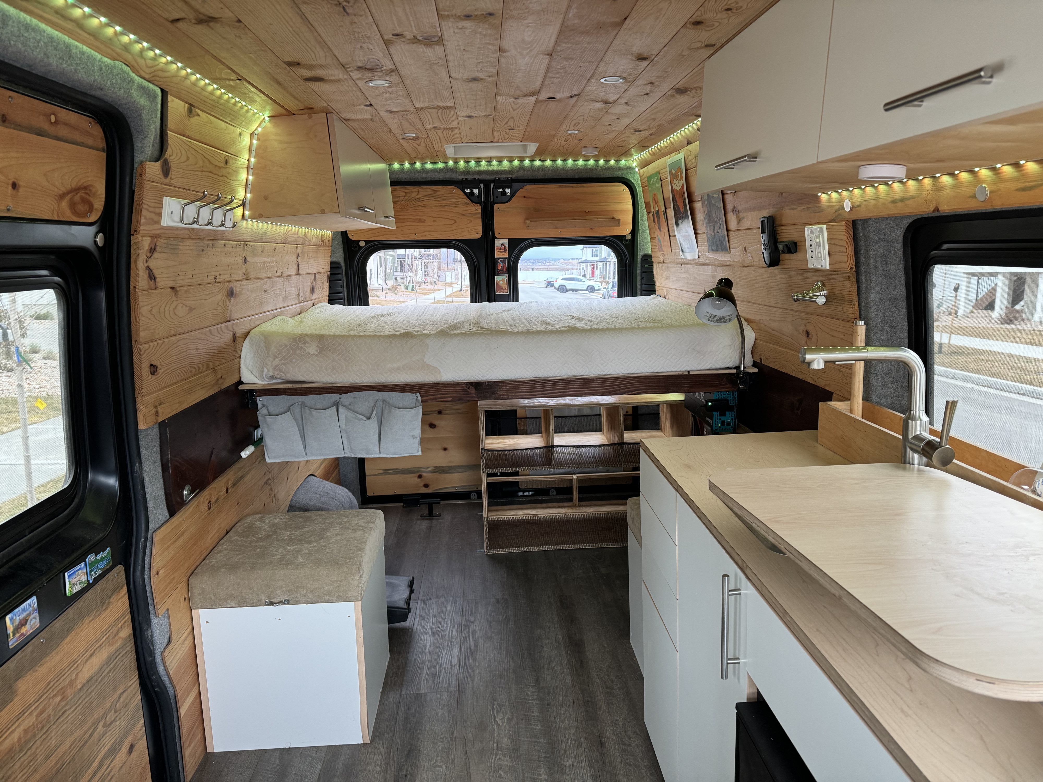 Modern rv rental interior with a cozy raised bed, wooden accents, and a compact kitchen counter.. Ram Promaster 2500 2020