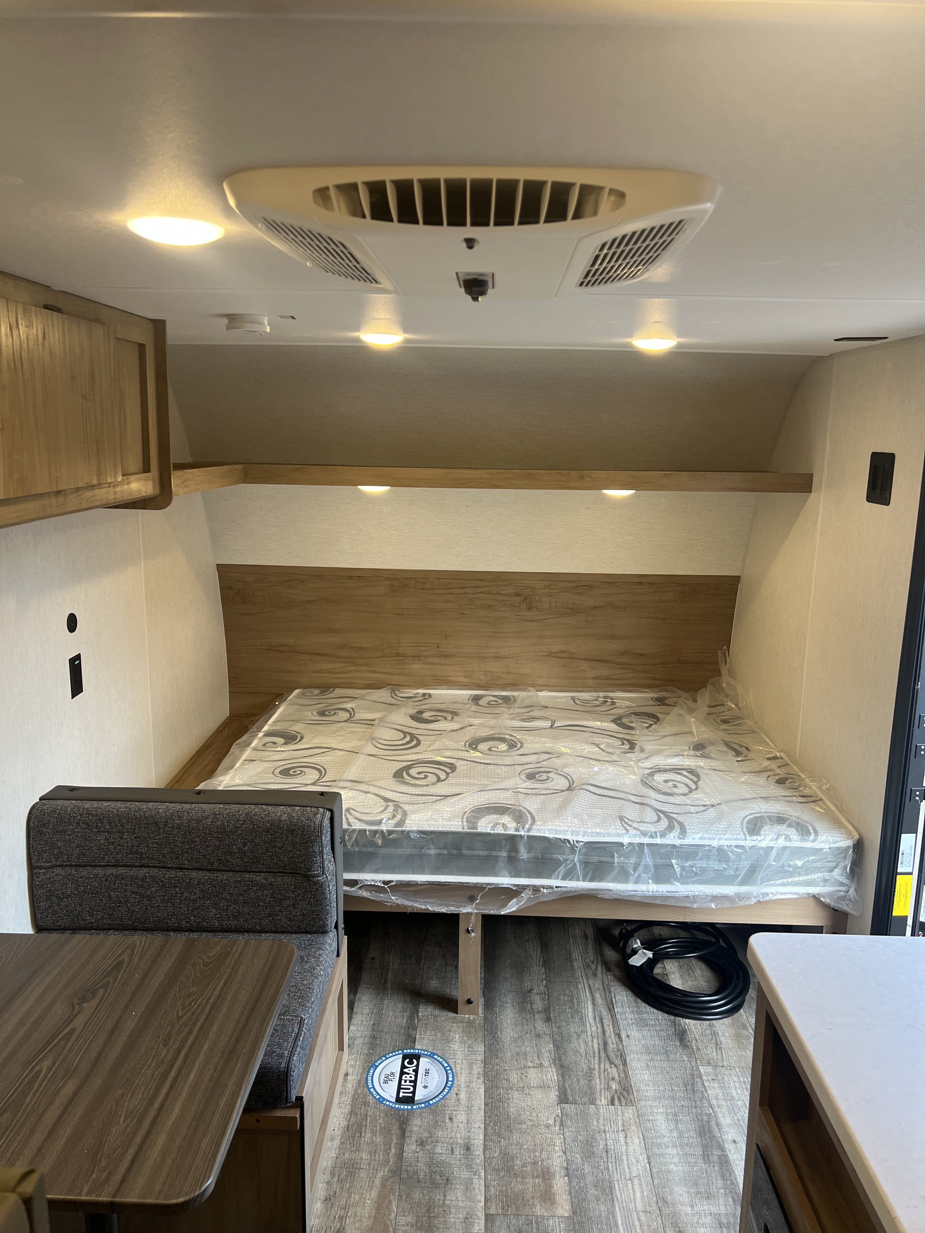 RV rental interior with a cozy bed area (mattress still wrapped), a dinette, and ceiling AC, ideal for travel.. Forest River Wolf Den 2024