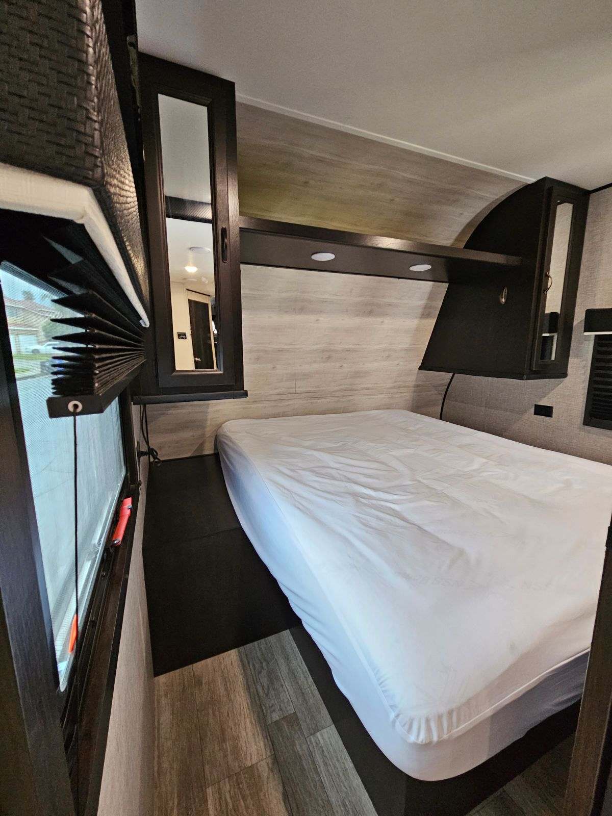 Explore this RV rental's cozy bedroom with a comfortable bed, mirrored storage, and window, perfect for your next trip.. Jayco Jay Flight SLX Rocky Mountain Edition 2022