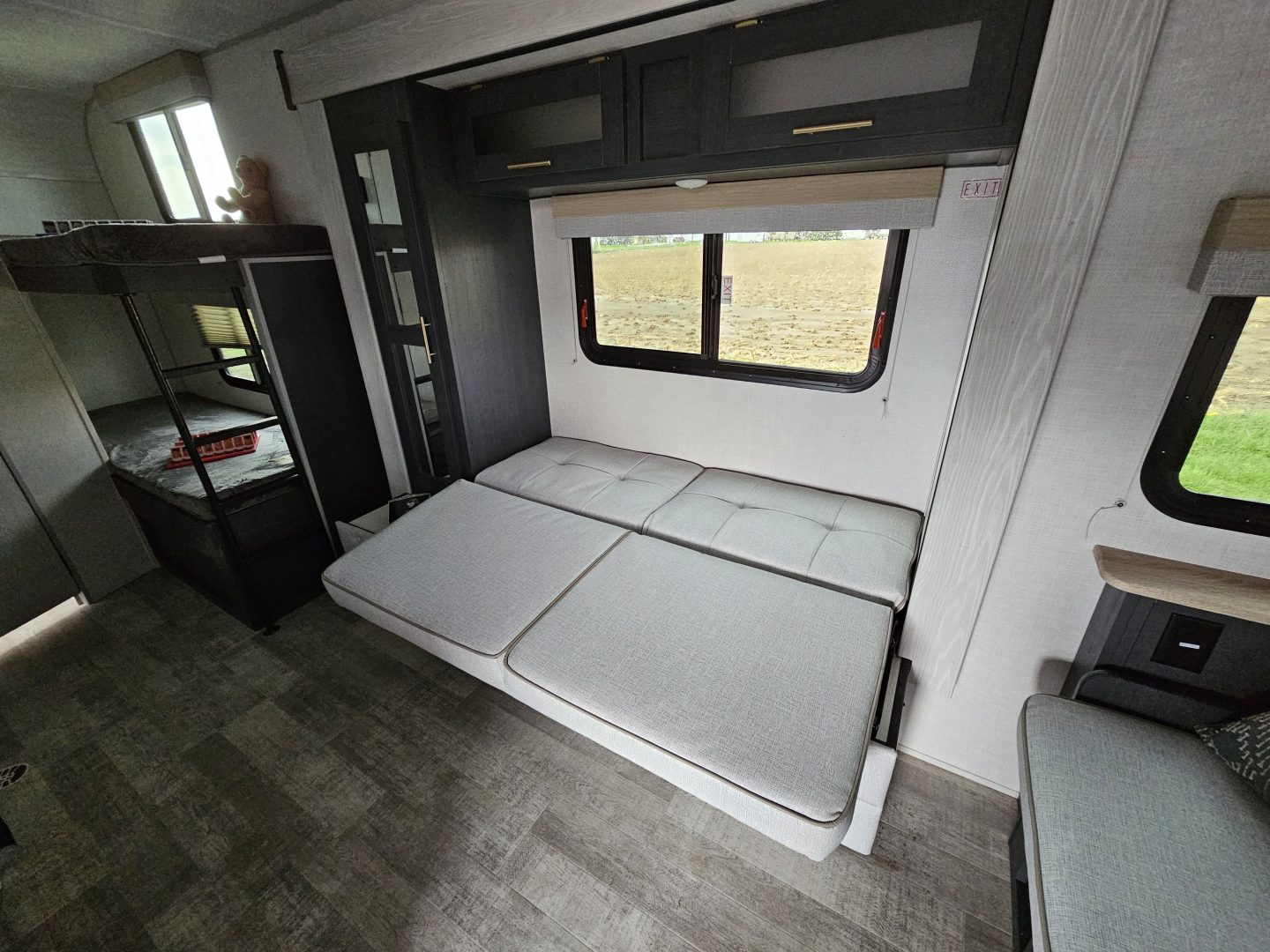 Spacious RV rental interior featuring bunk beds, a convertible sofa, and large windows with field views.. R-Pod R-Pod Trailer 2022