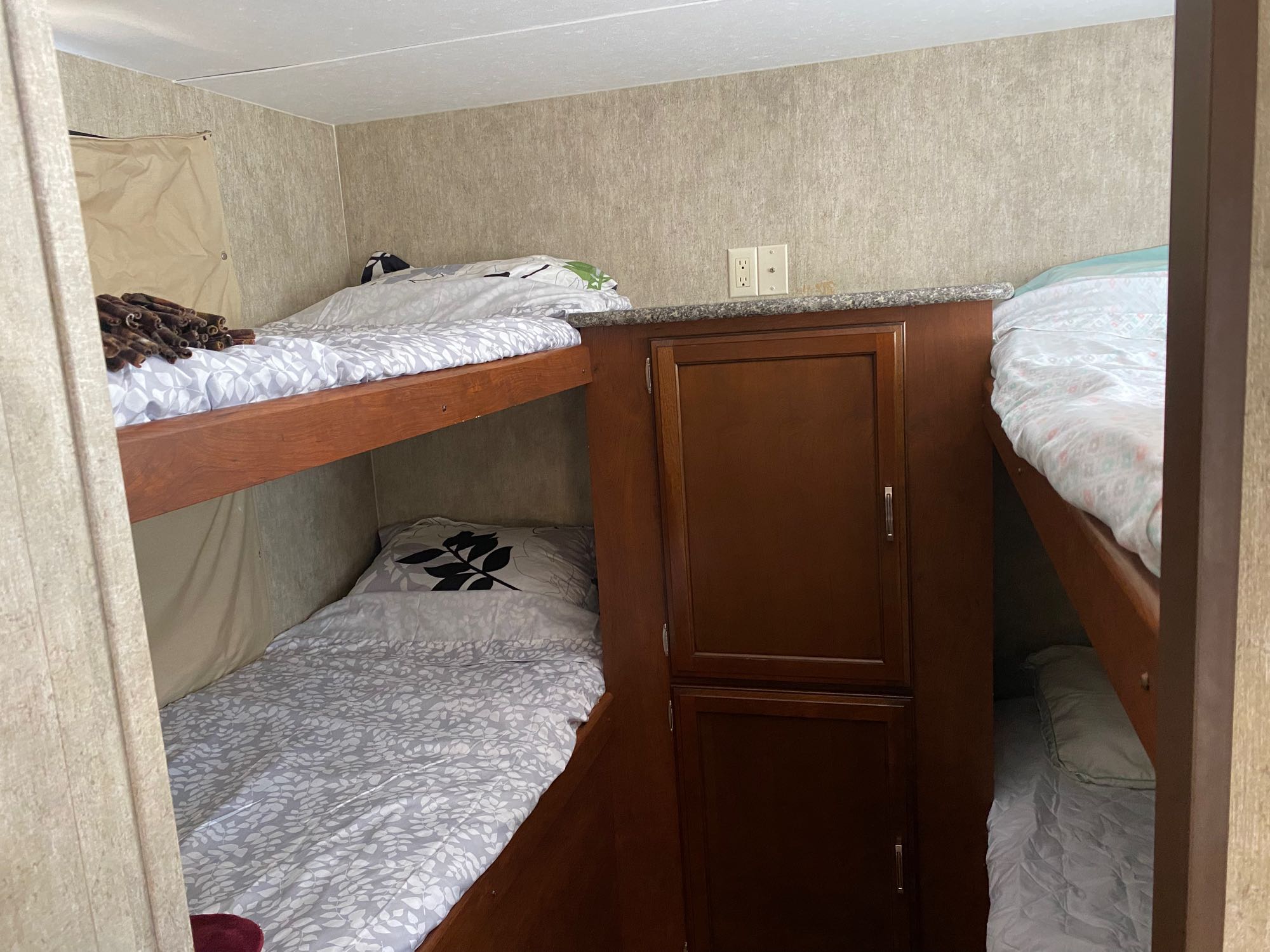 RV rental bunk beds: multiple sleeping areas, a central cabinet, and power outlets for convenience.. Keystone RV Passport Grand Touring 2015