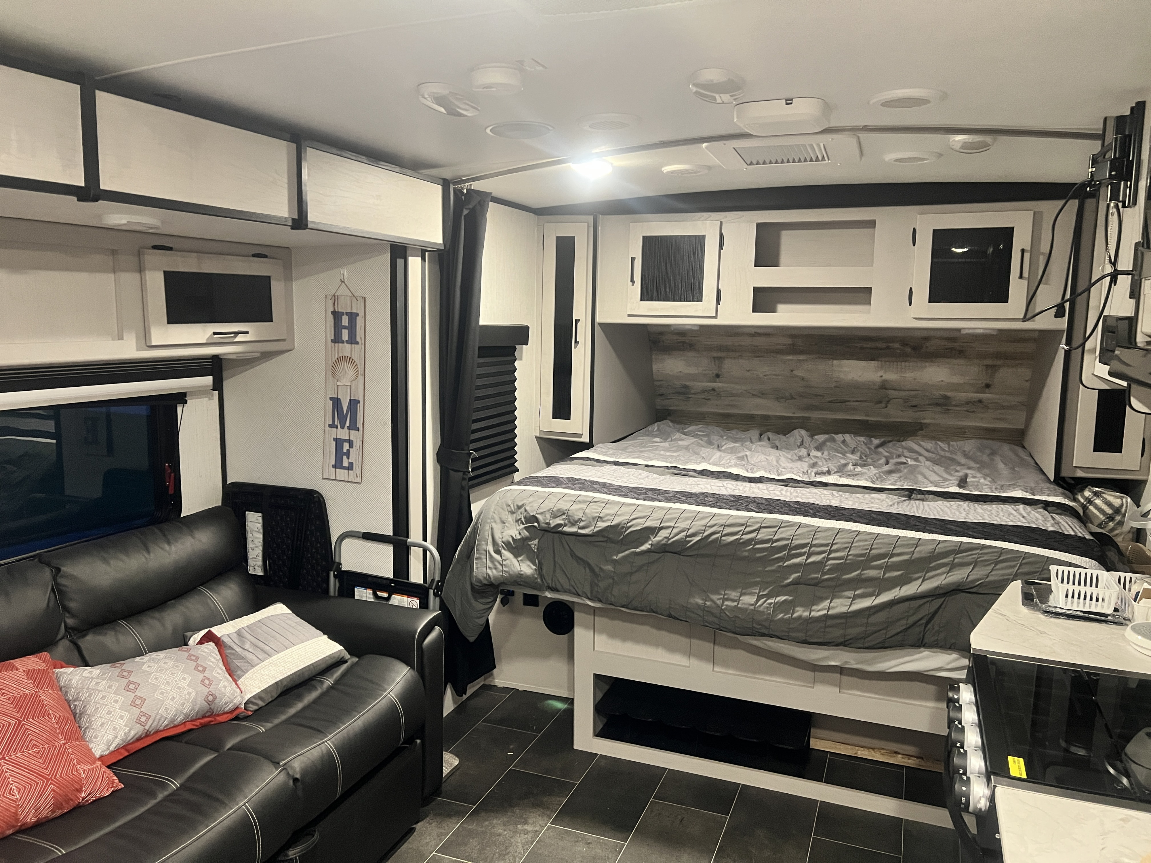 Explore this compact RV rental interior! Featuring a comfortable bedroom with bed, cabinets, and a living area with a sofa.. Heartland RVs Mallard 2022