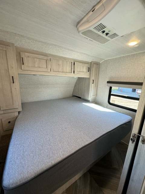 Cozy RV rental bedroom: large bed, light wood cabinets, AC unit. Perfect for comfortable travel and rest.. East to West Delta Terra 2022