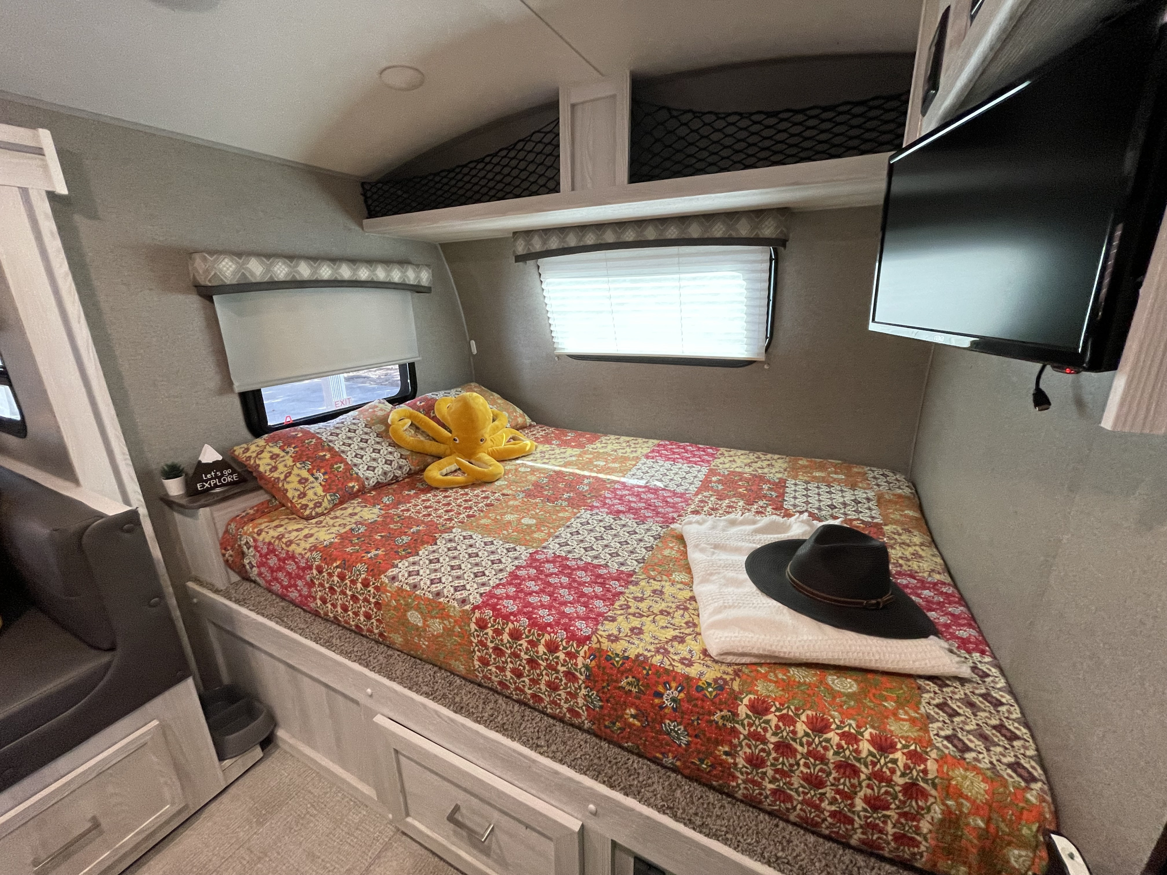 Cozy RV rental bedroom featuring a colorful quilt, yellow octopus, and TV. Ready for your next travel adventure!. Forest River Flagstaff E-Pro 2021