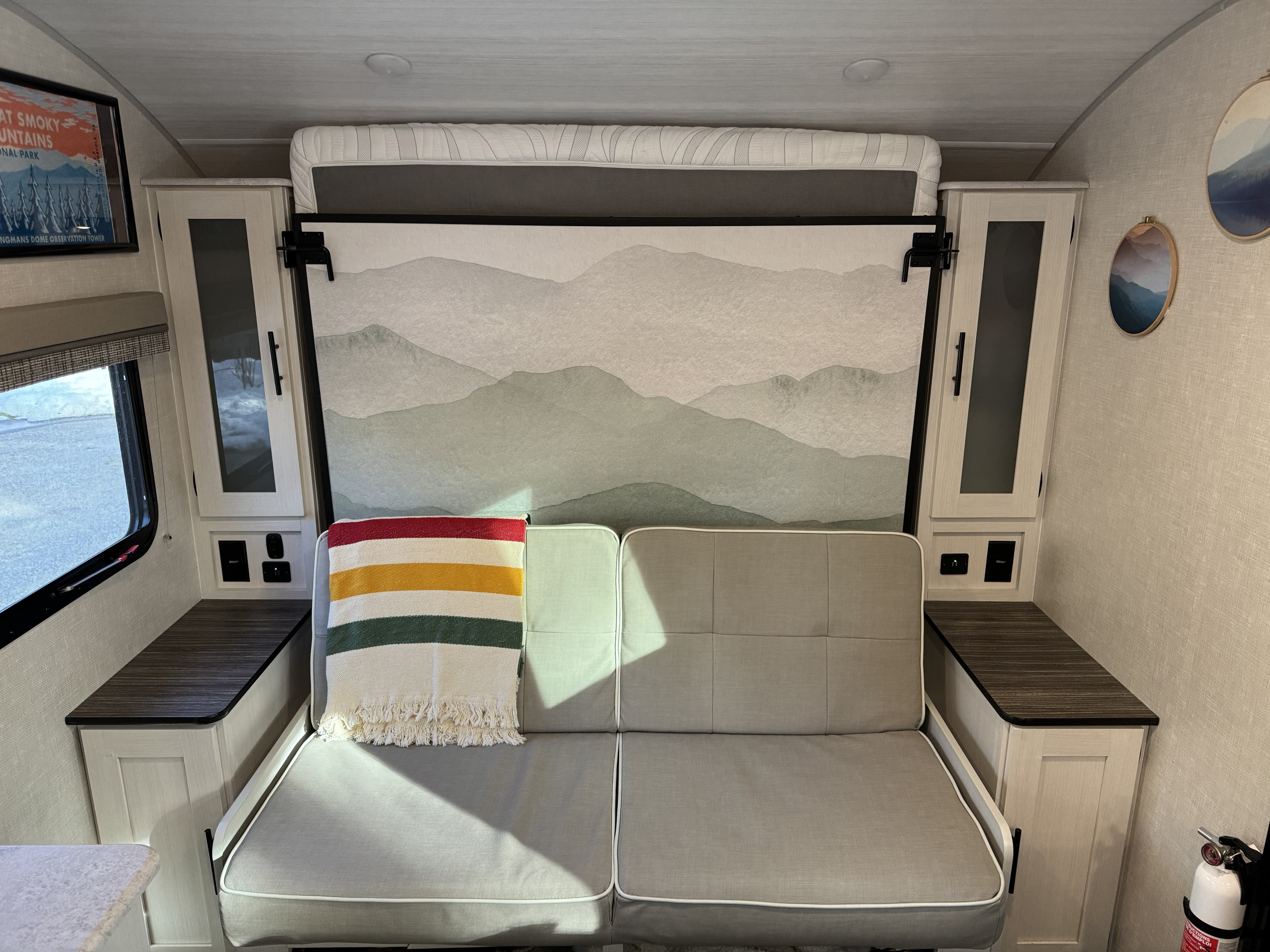 Cozy RV rental interior featuring a versatile sofa that converts to a bed, flanked by storage cabinets and artistic decor.. R-Pod R-Pod Trailer 2022
