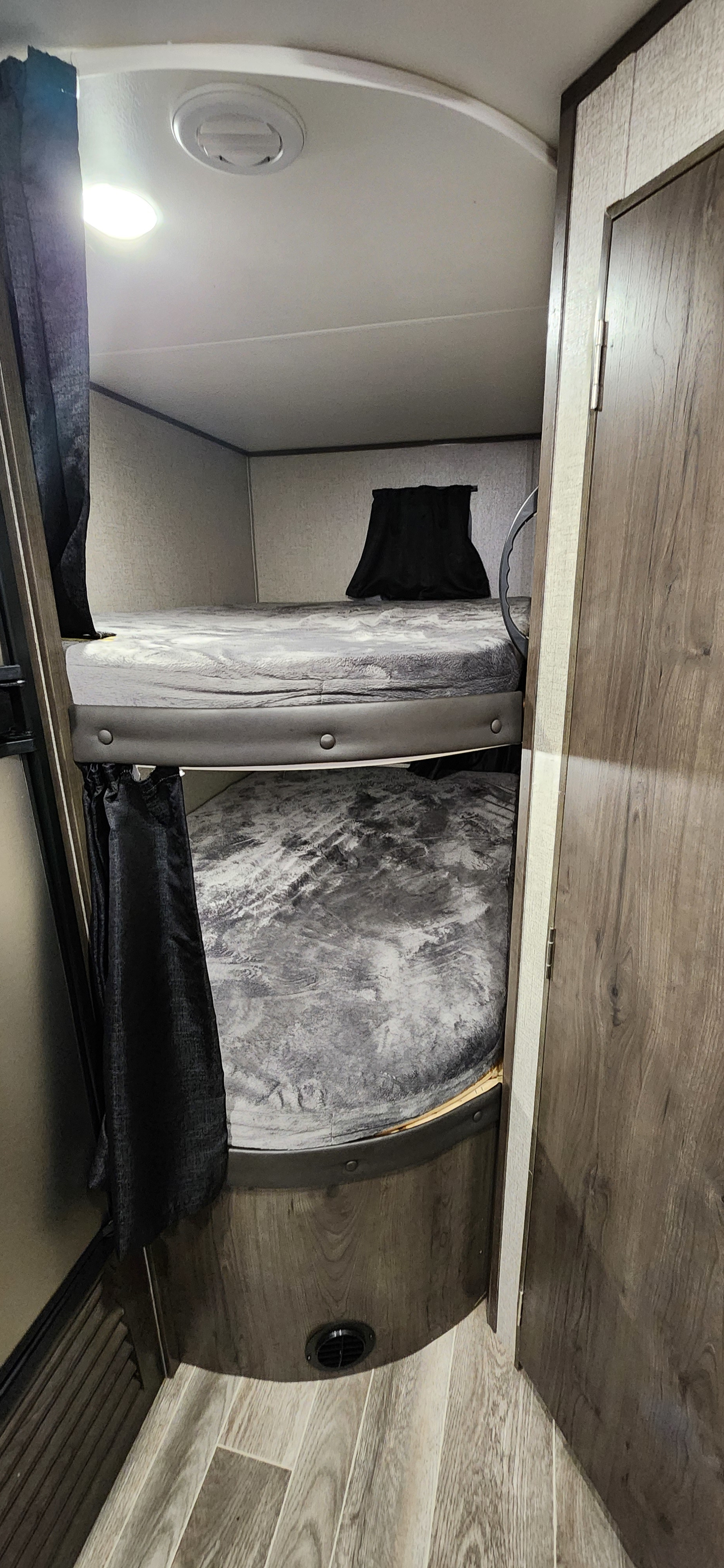 Inside an RV rental: two stacked bunk beds with gray plush blankets, dark privacy curtains, wood-look floors, and ceiling vents.. Jayco Jay Flight SLX 2021