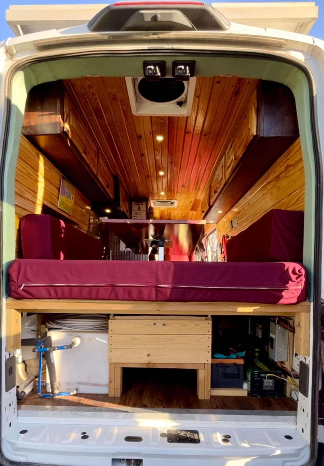 Step inside this custom wood-paneled camper van, ideal for an rv rental. Features a comfy bed, storage, and off-grid utilities.. Ford Transit 350 High Roof EXT 2020