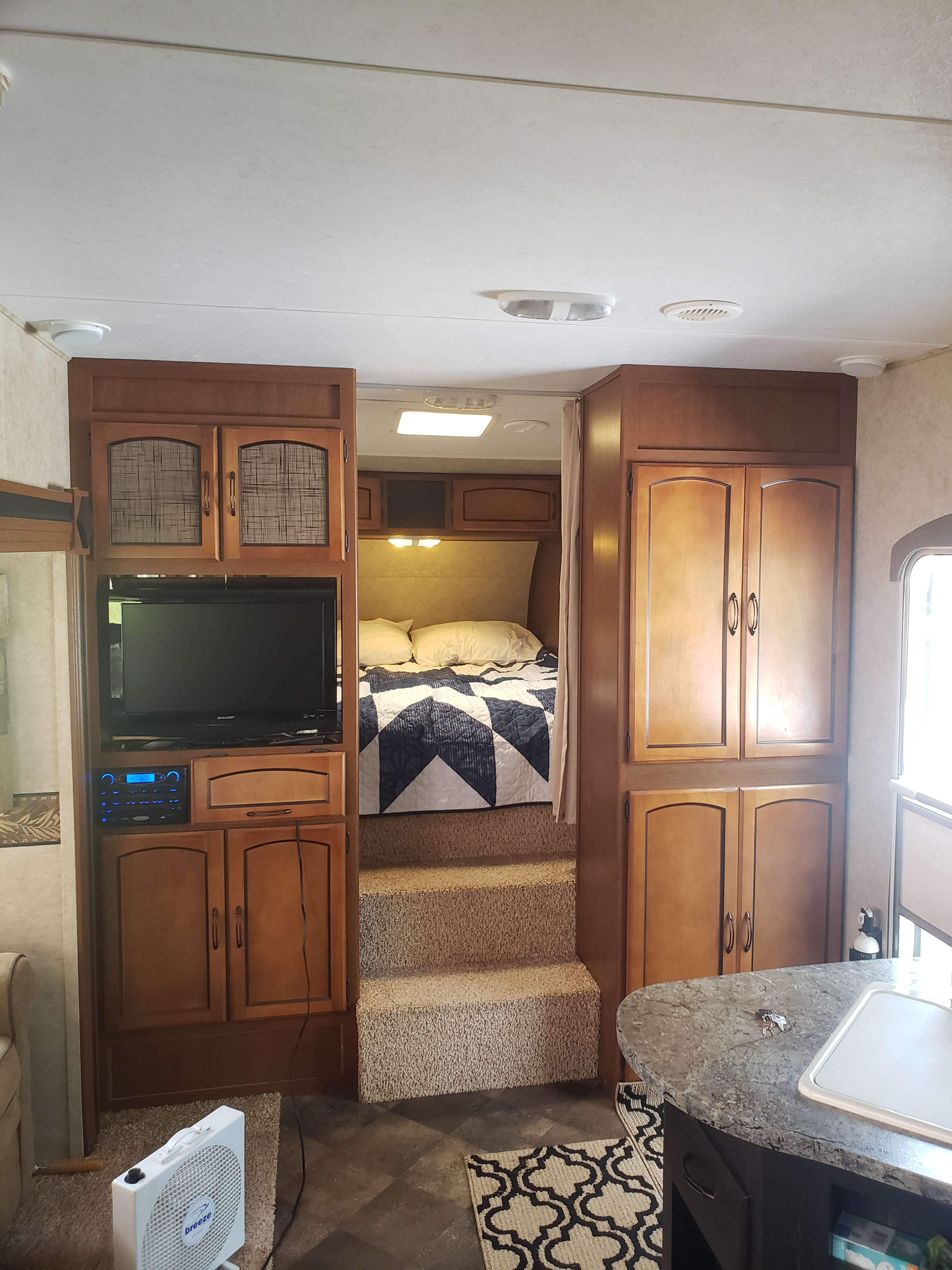 This **rv rental** interior features a raised bedroom, entertainment system, and kitchen area, showcasing comfortable living space.. Keystone RV Springdale 2013