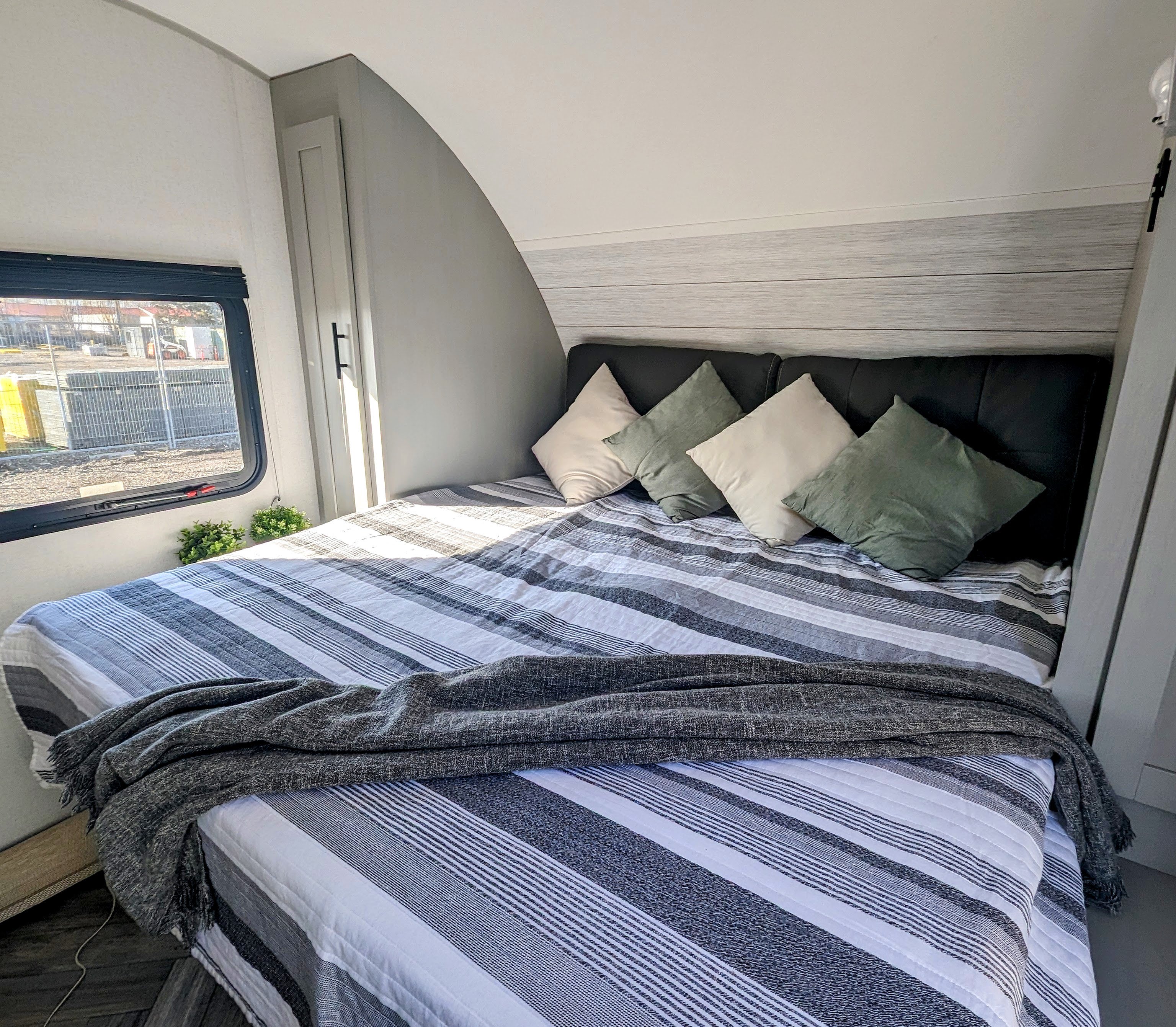 Spacious RV rental bedroom featuring a comfy bed with striped bedding, throw, and four pillows.. Forest River Wildwood FSX 2021