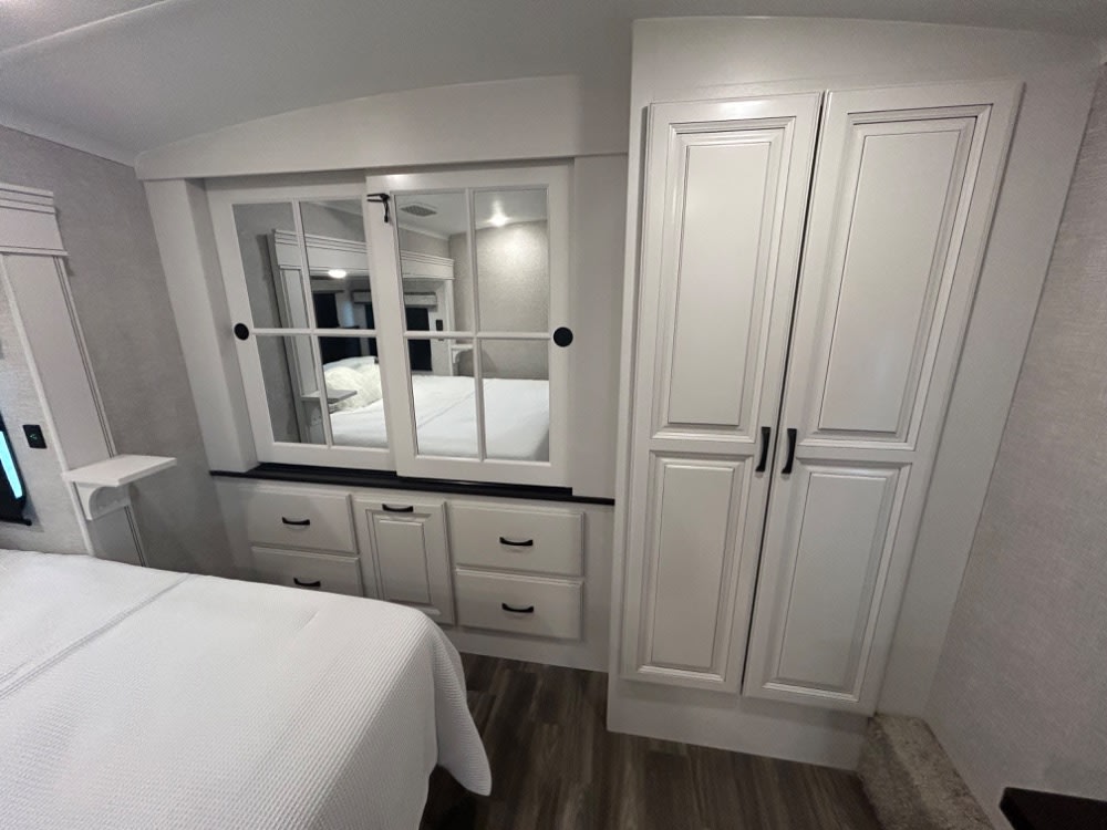Comfortable RV rental bedroom featuring built-in mirrored storage, wardrobe, and drawers. Ideal for travel.. Jayco North Point 2025